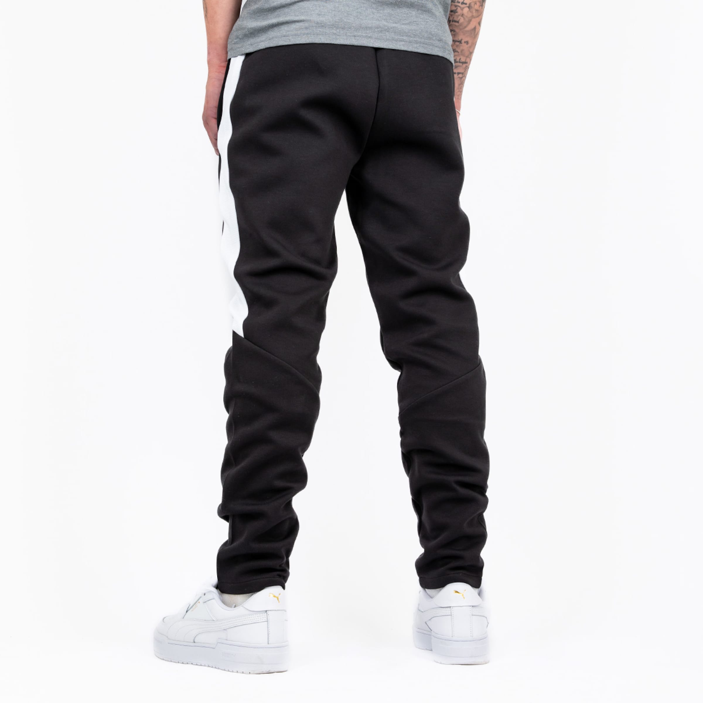 Mann von hinten in schwarzen Jogginghosen mit weißen Seiteneinsätzen und weißen Sneakers.