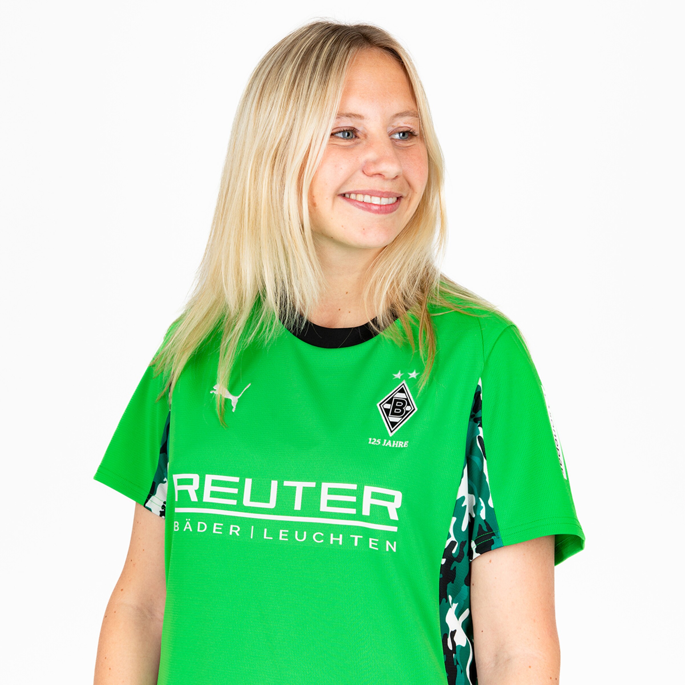 A blonde woman wearing a green jersey featuring the Borussia Mönchengladbach logo.