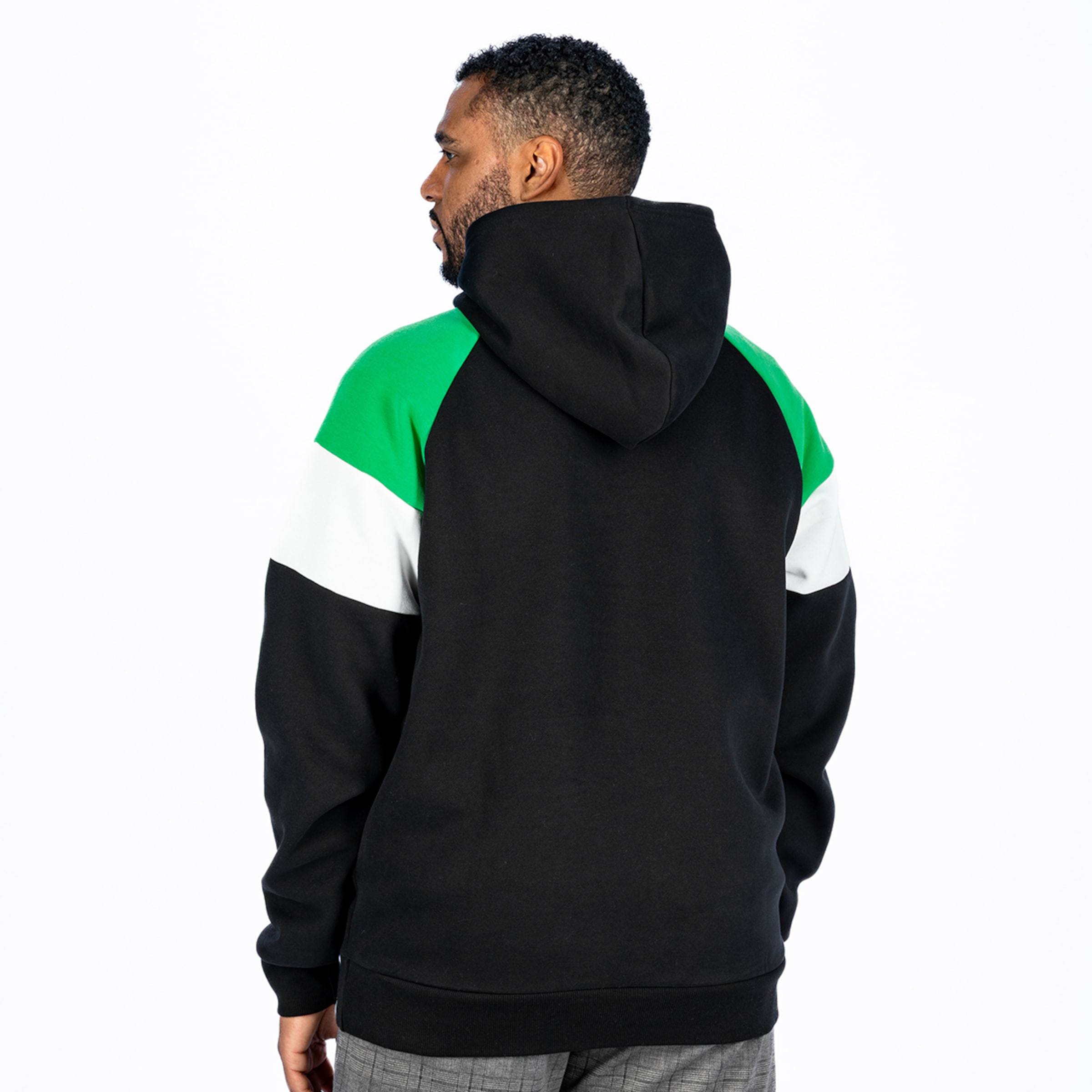 Rückansicht eines Mannes in einem schwarz-grün-weißen Colorblock-Hoodie vor weißem Hintergrund.