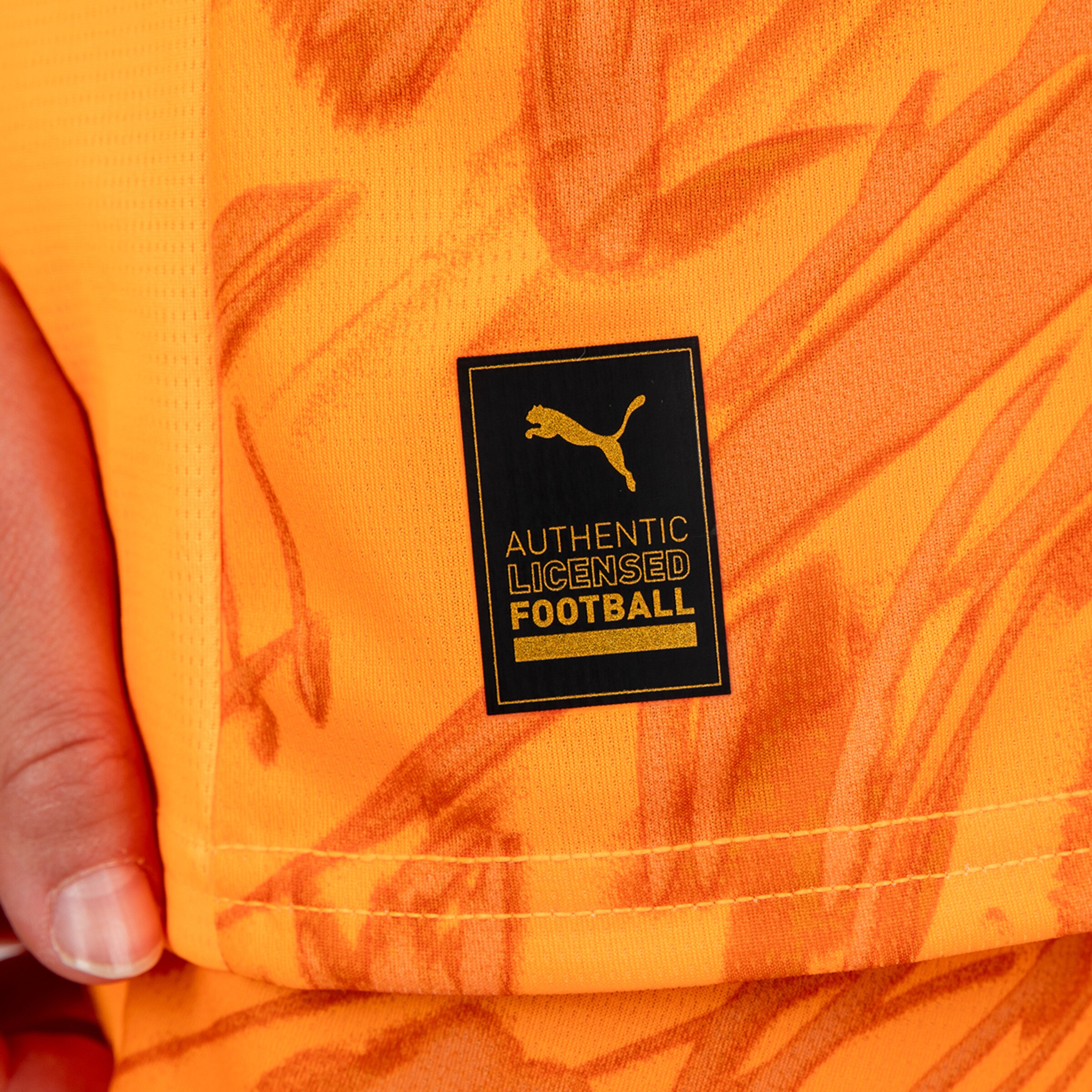 Authentisches lizenziertes Fußball-Tag auf einem orangefarbenen Ball von Puma.