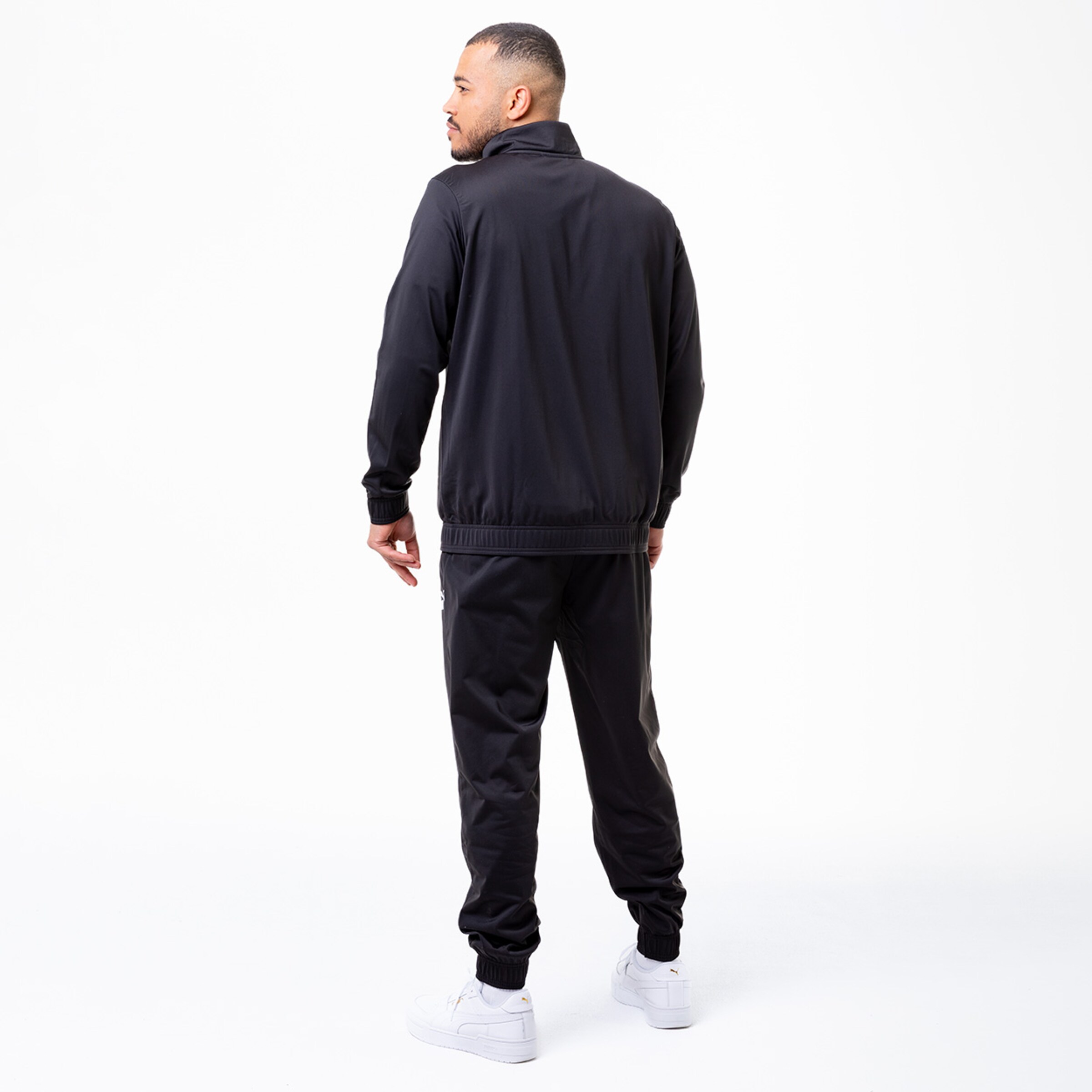 Ein Mann in schwarzem Trainingsanzug von hinten.