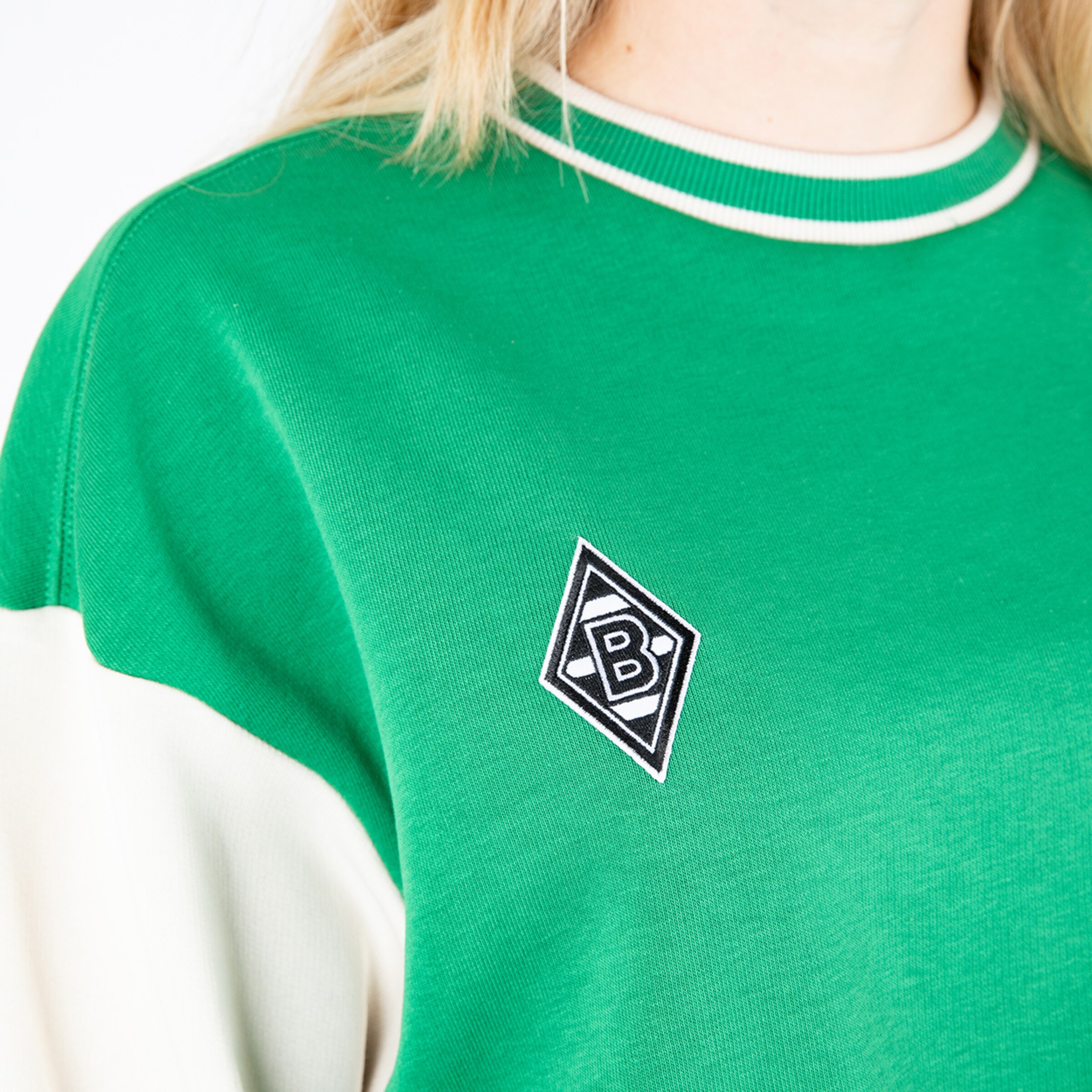 Grünes Sweatshirt mit einem weißen Ärmel; auf der Brust das Borussia Mönchengladbach Logo.