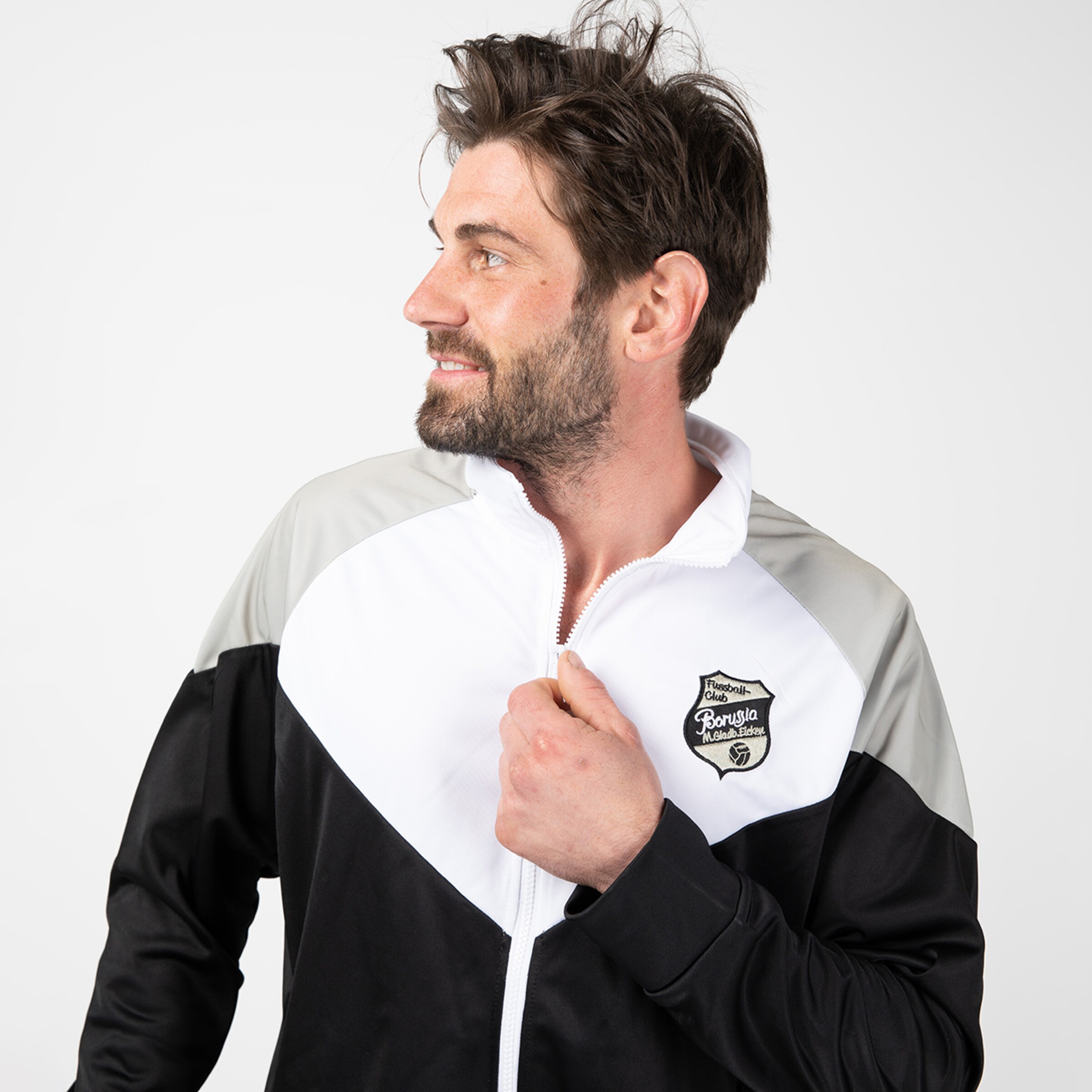 Mann trägt eine schwarz-weiße Sportjacke mit dem Borussia Mönchengladbach-Logo.
