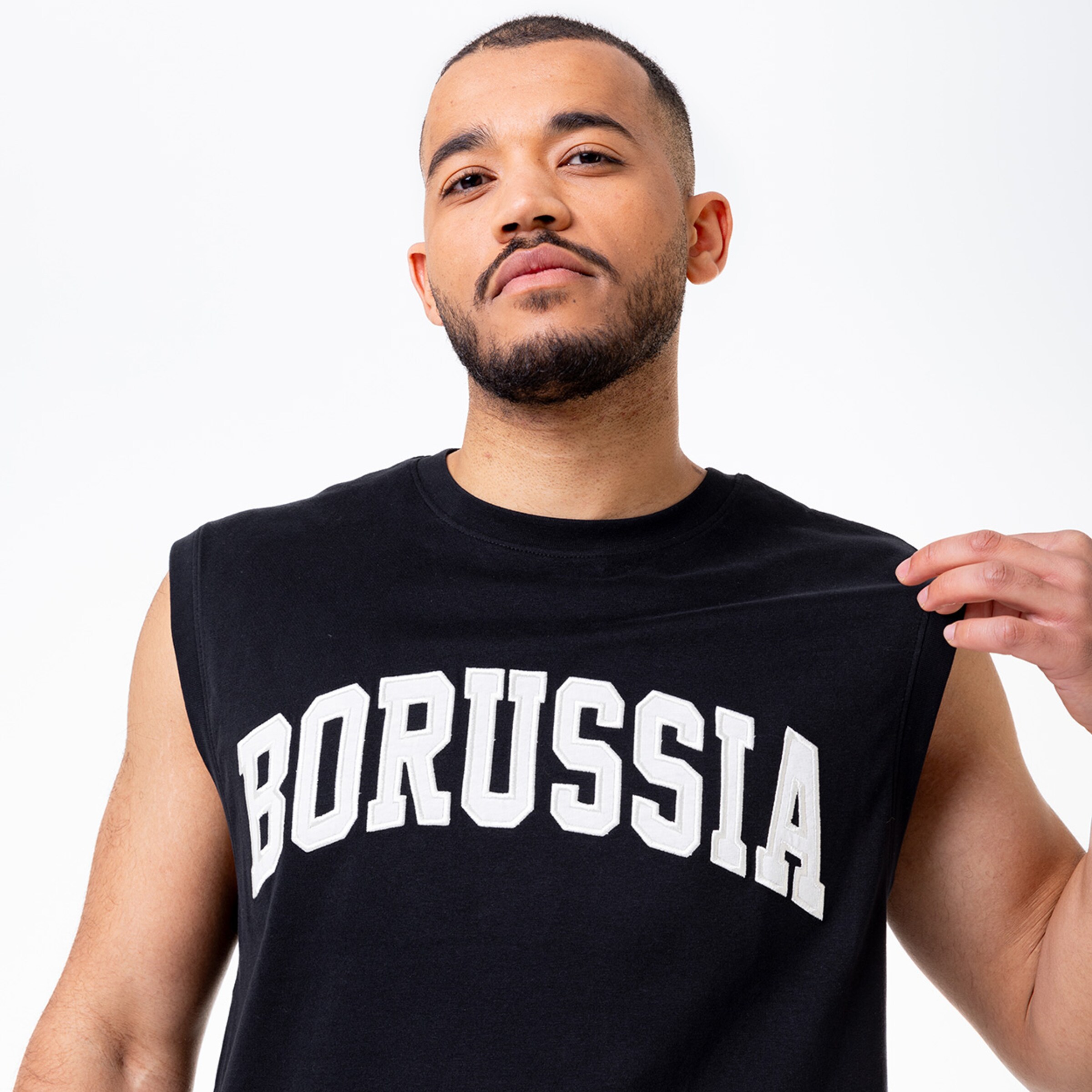 Ein Mann trägt ein ärmelloses schwarzes Oberteil mit dem Aufdruck BORUSSIA.