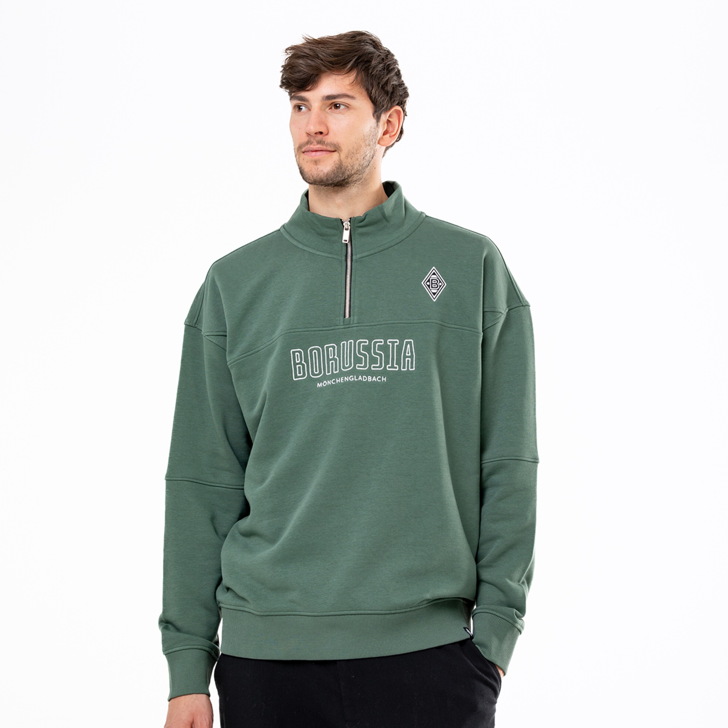 Mann in grünem Borussia Mönchengladbach Sweatshirt mit Half-Zip und weißem Logo-Print vor weißem Hintergrund.