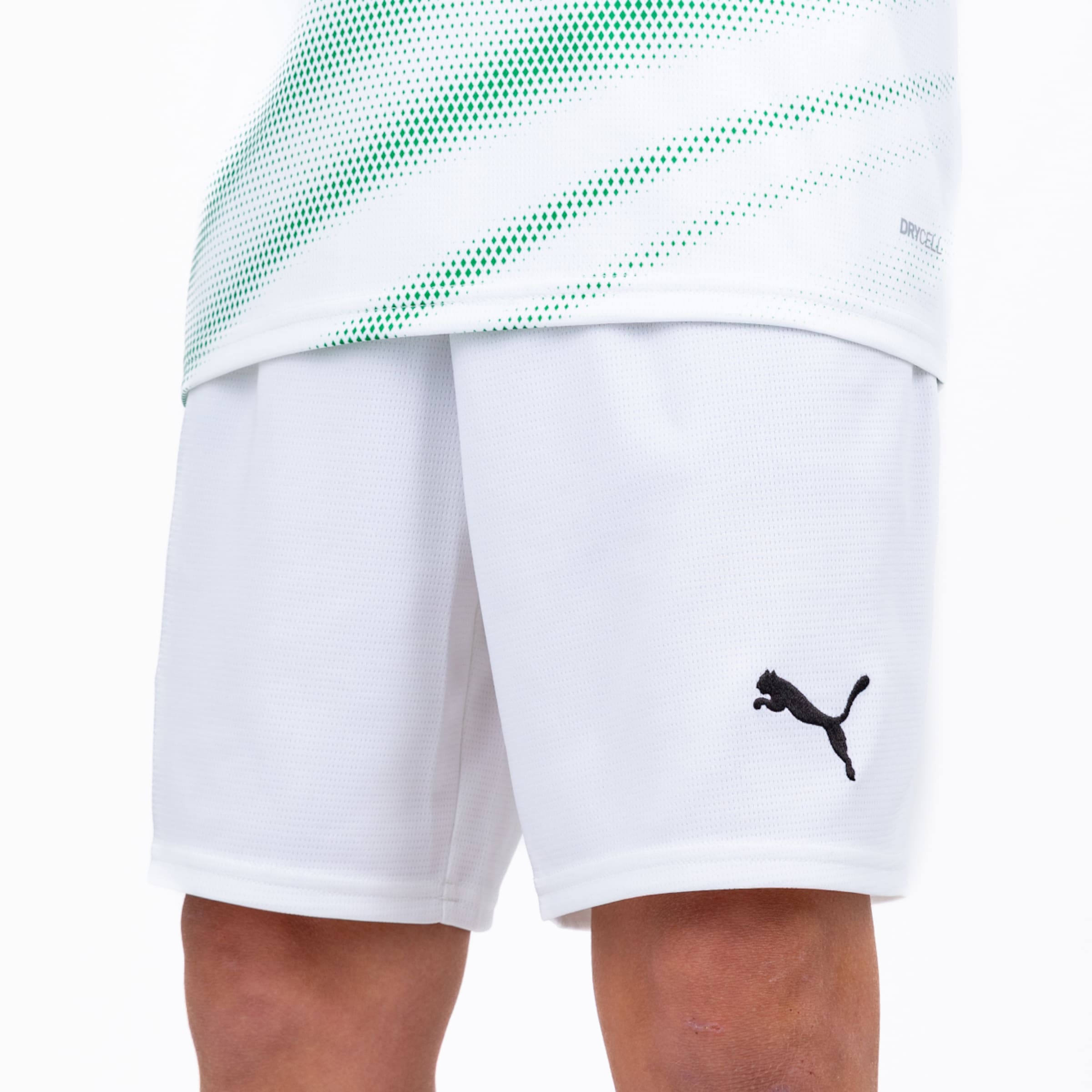 Weiße Puma-Sportshorts mit schwarzem Logo, getragen zu einem weißen Trikot mit grünem Punktmuster und Drycell-Technologie.