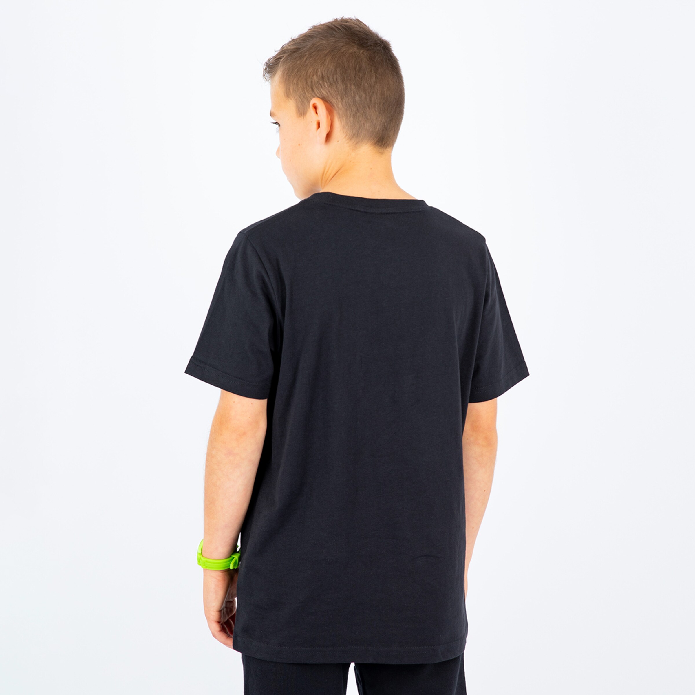 Ein Junge steht mit dem Rücken zur Kamera trägt ein schwarzes T-Shirt und platzierende Sportbekleidung.