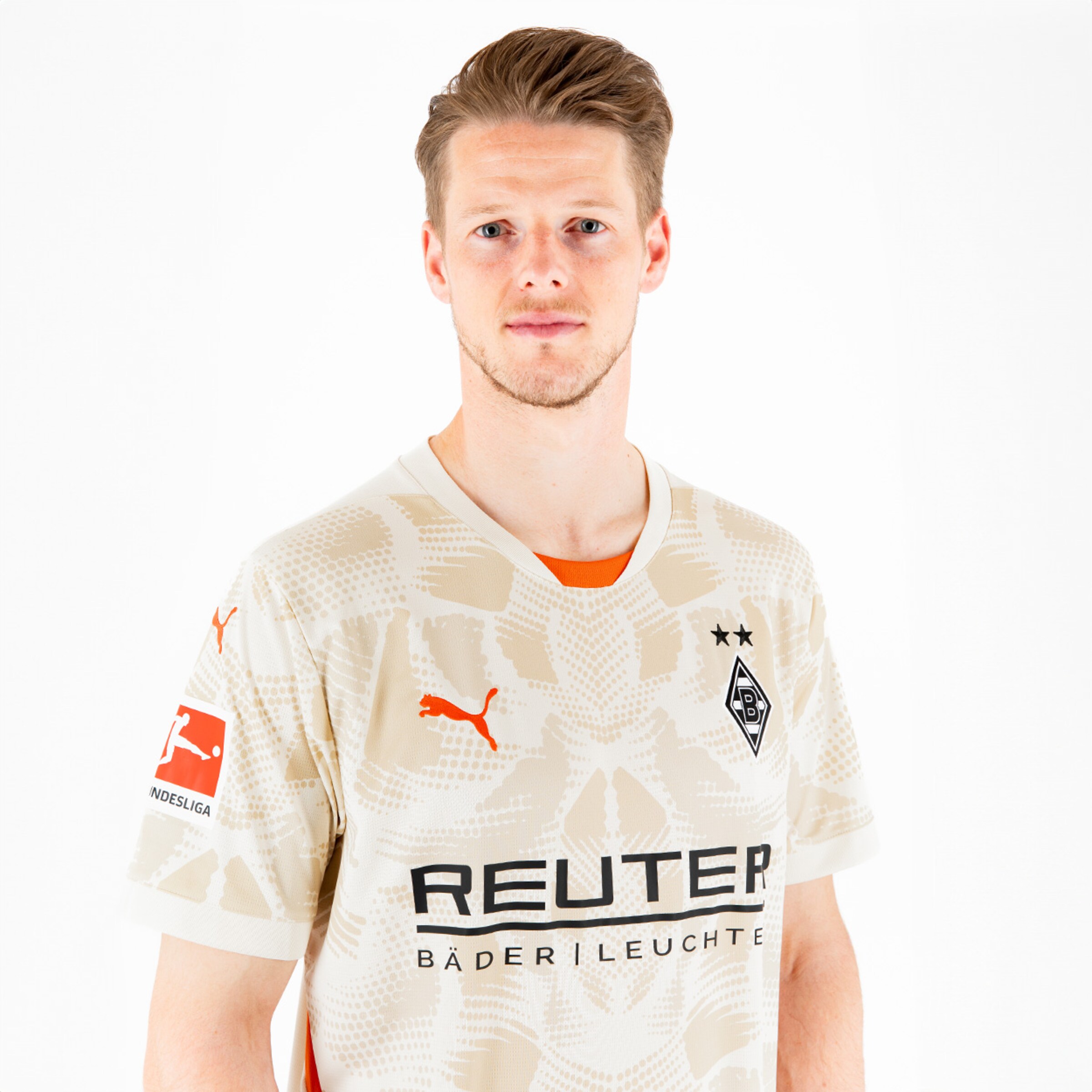 Ein Spieler des Borussia Mönchengladbach in einem beigen Trikot mit dem Vereinslogo und Sponsorennamen.