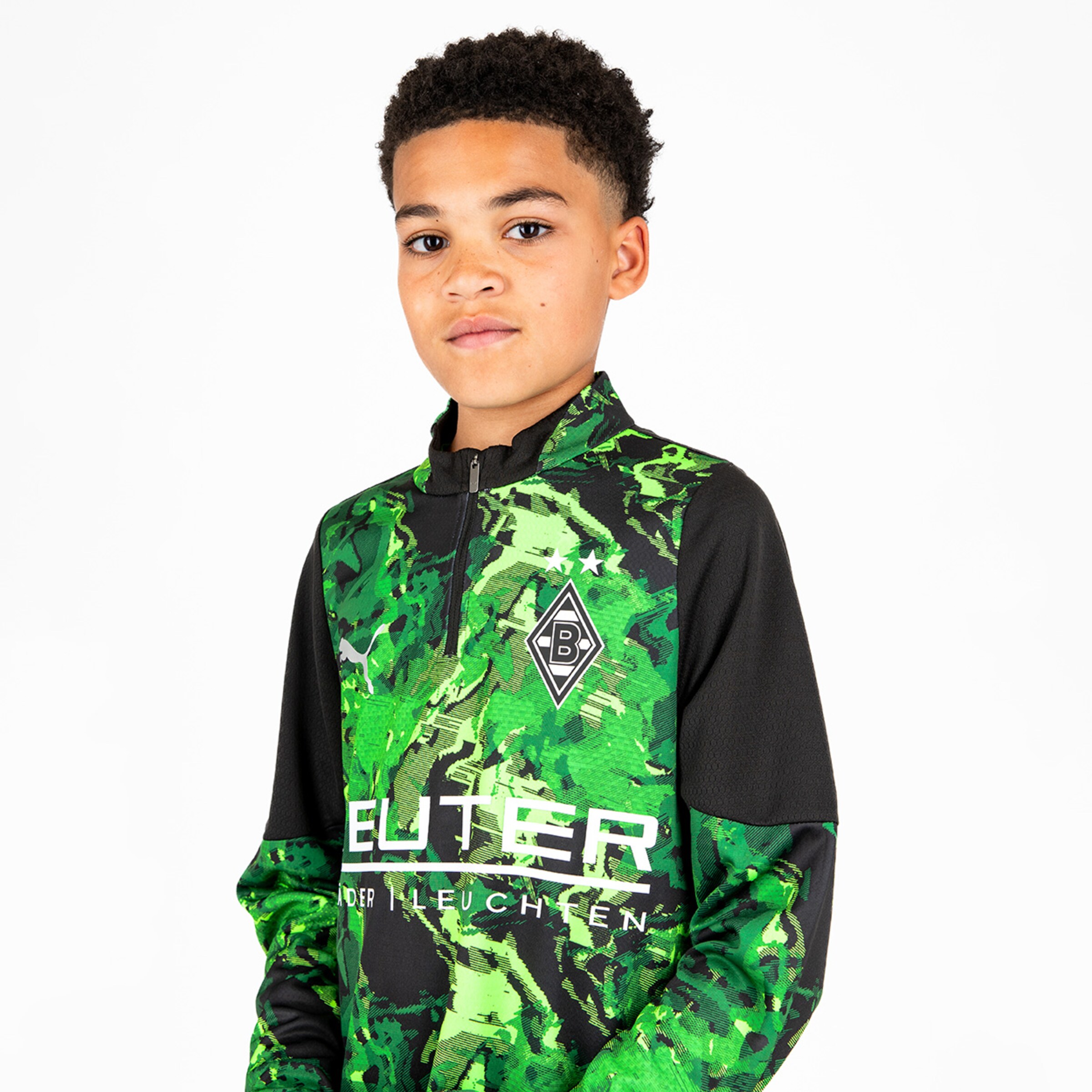 Junge im grünen Trainingsanzug von Borussia Mönchengladbach mit Logo auf der Brust Blick nach vorne.