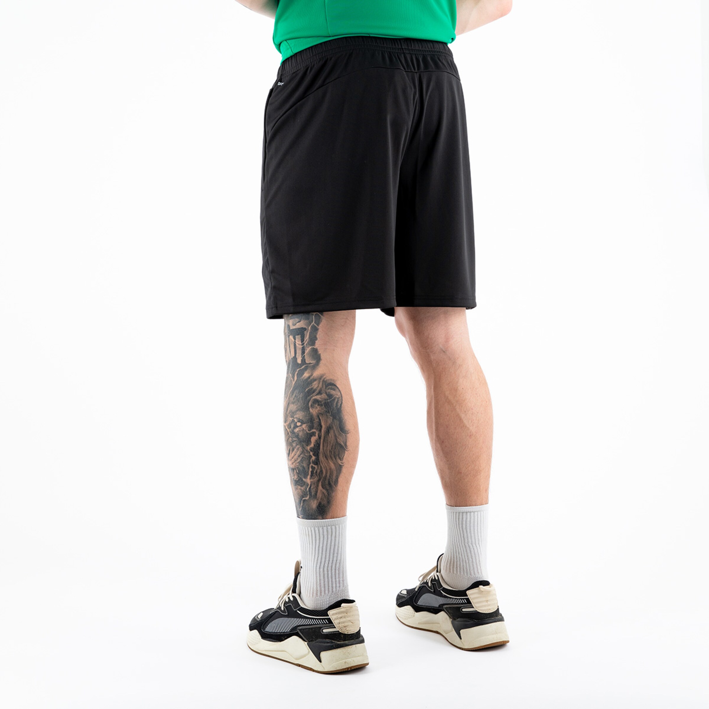 Person mit kurzen schwarzen Hosen und einem tätowierten Bein.