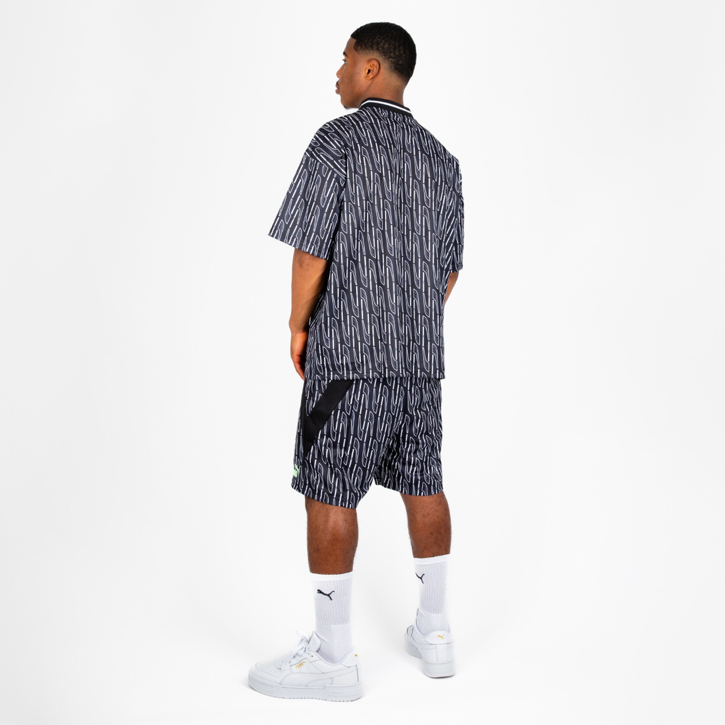 Mann stehende von hinten in sportlicher Bekleidung bestehend aus kurzärmeligem Shirt und Shorts mit grafischem Muster.