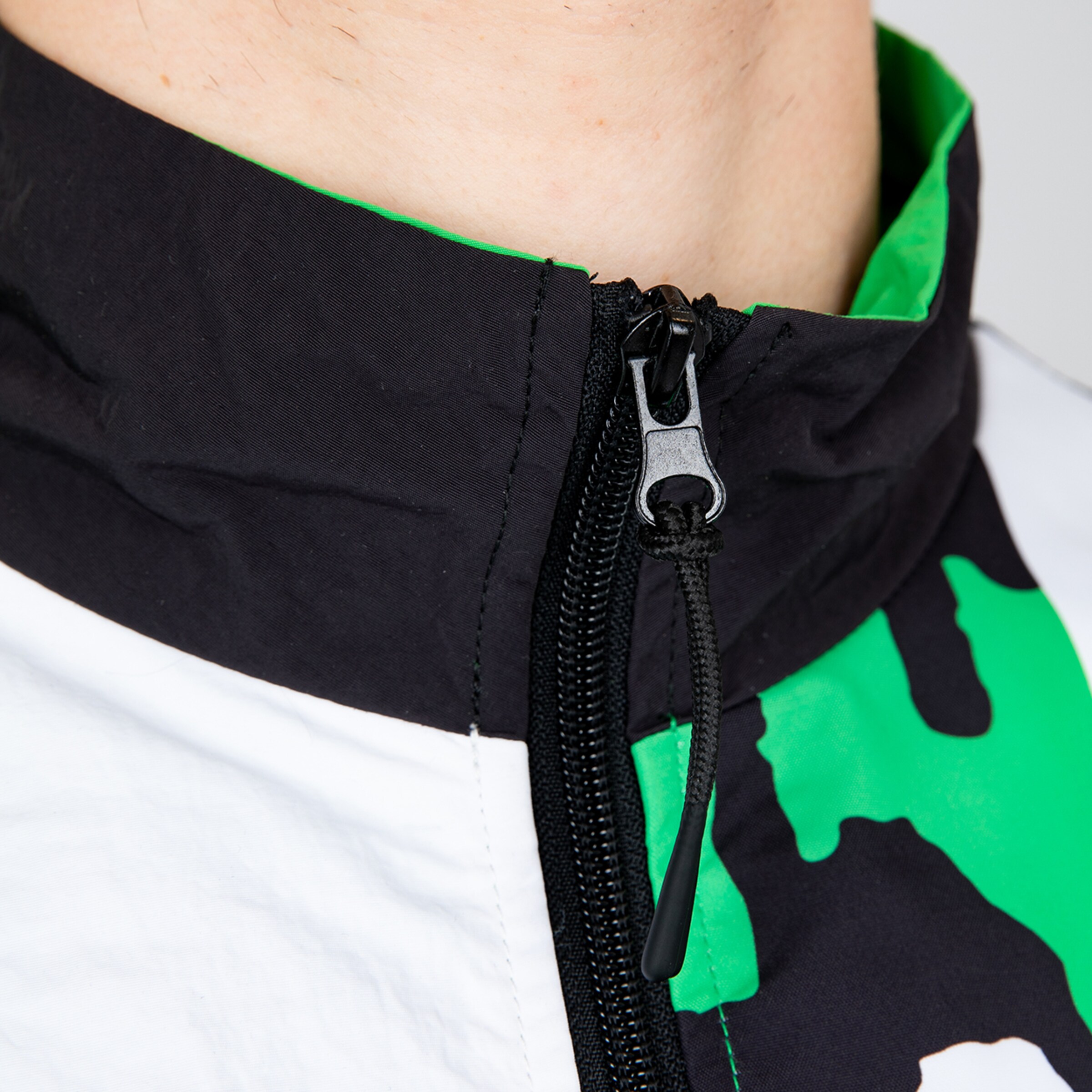 Close-up of a zipper on a sporty top in black and green.