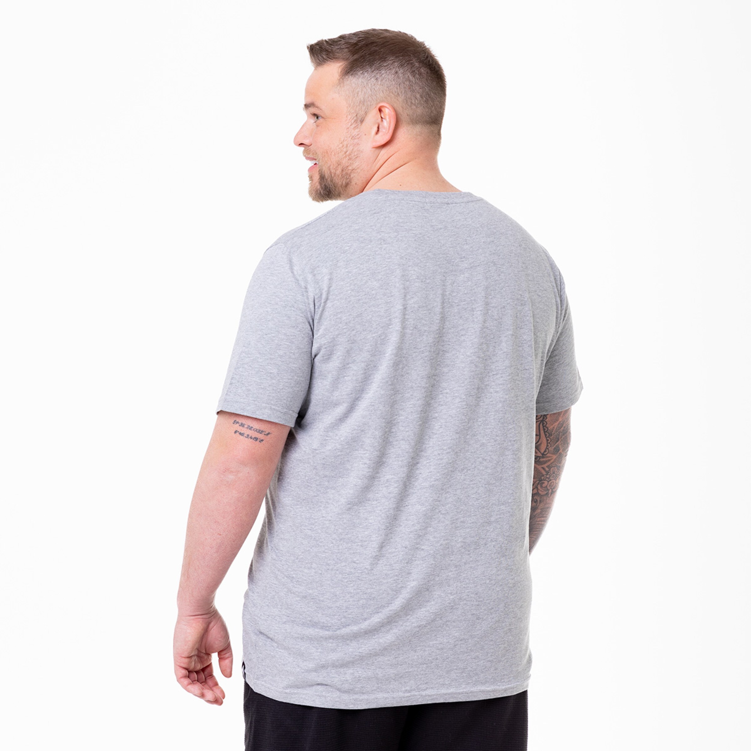 Mann mit kurzen Ärmeln und grau melierten T-Shirt von hinten gesehen. Tattoo am linken Arm.