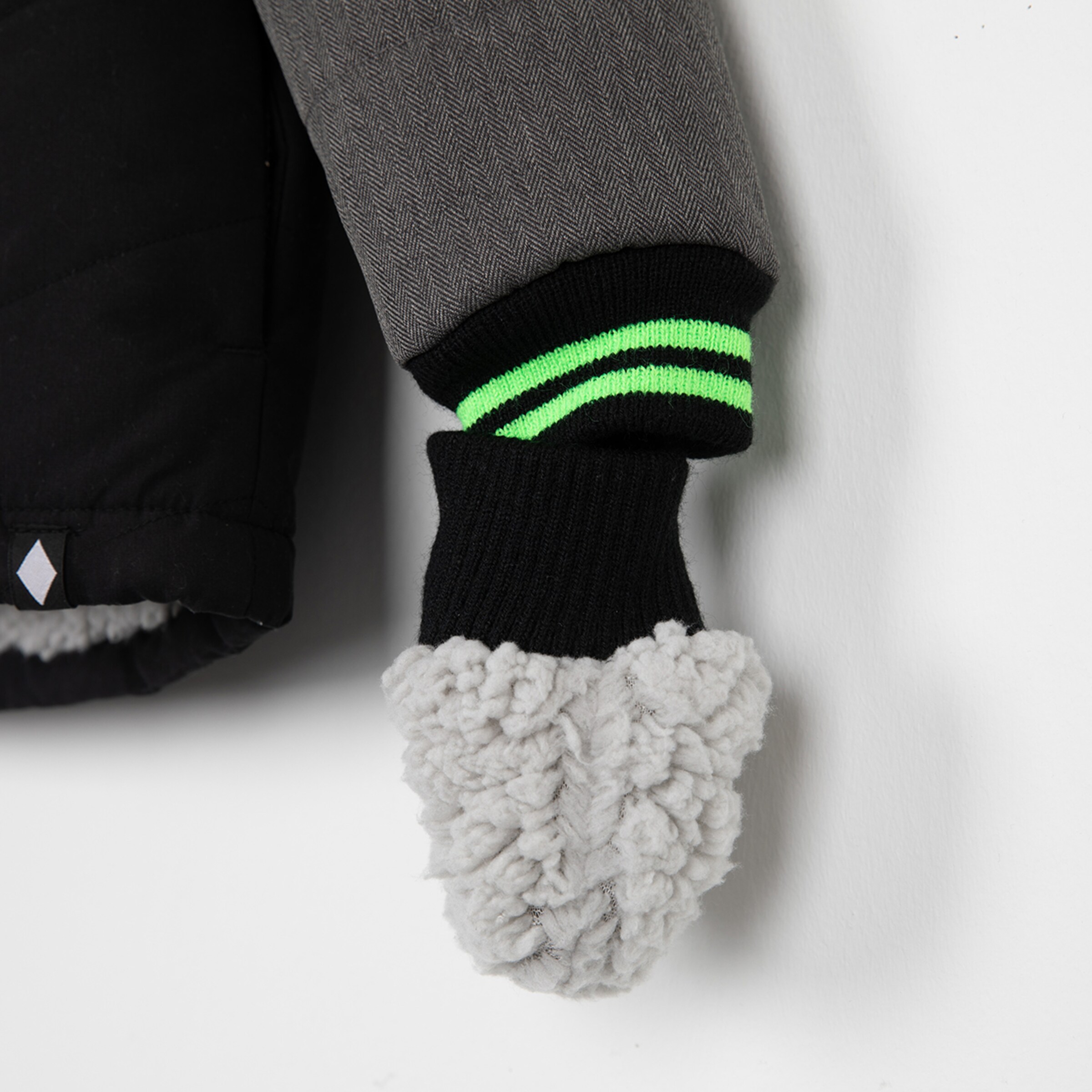 Gray jacket sleeve with green striped cuff and gray plush trim.