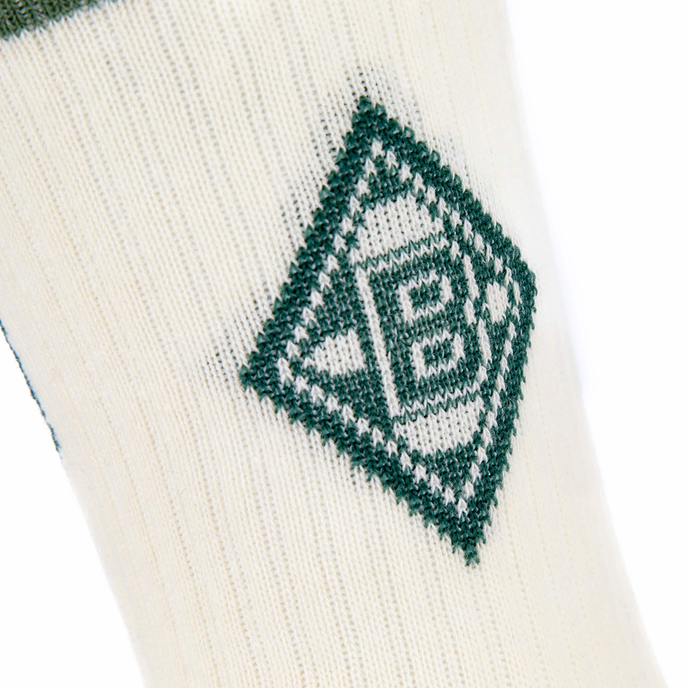 Detailansicht eines cremefarbenen Strickgewebes, möglicherweise einer Socke, mit einem dunkelgrünen Rautenmuster, das das verschlungene 'B'- und 'M'-Logo von Borussia Mönchengladbach zeigt.