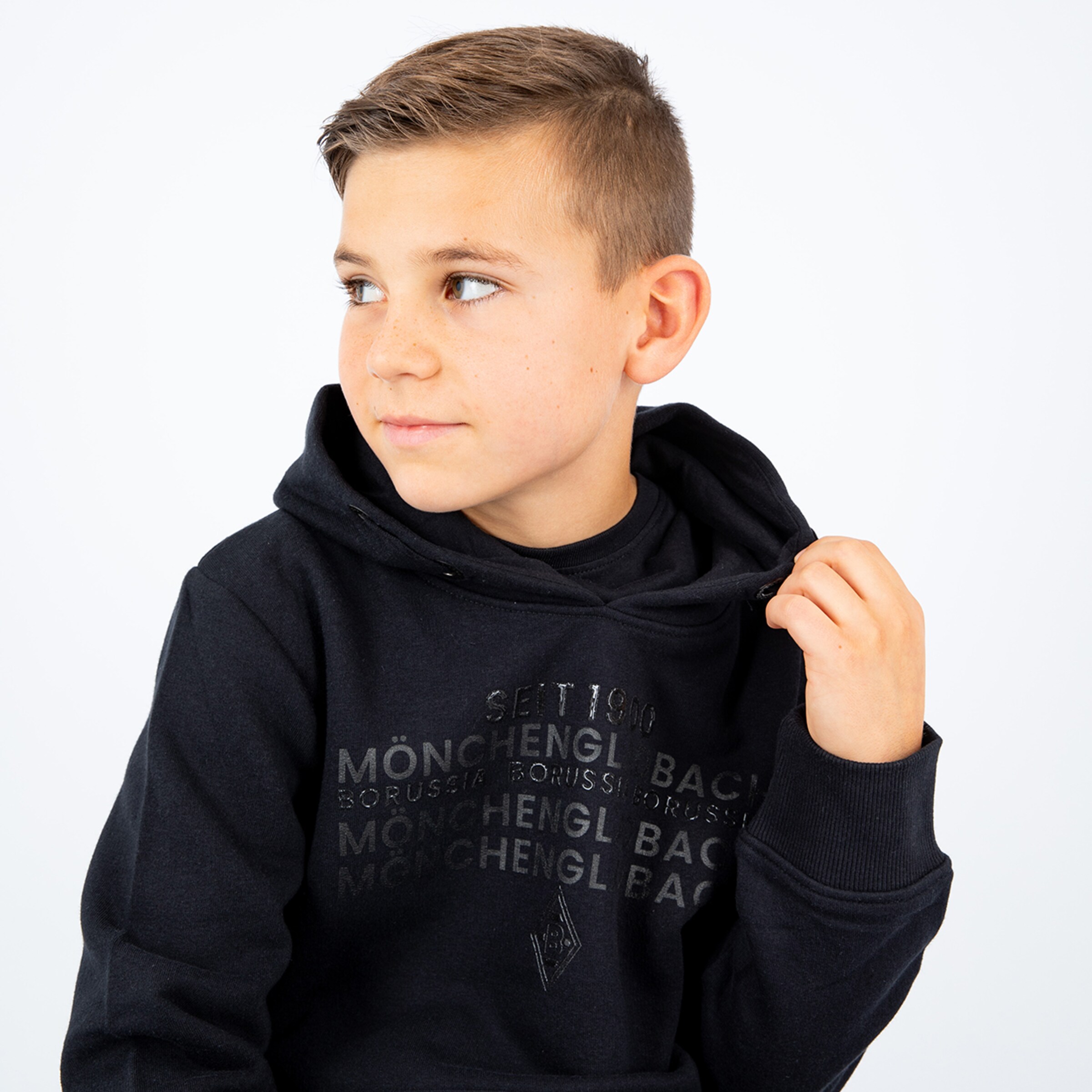 Ein Junge in einem schwarzen Hoodie mit dem Aufdruck Borussia Mönchengladbach.