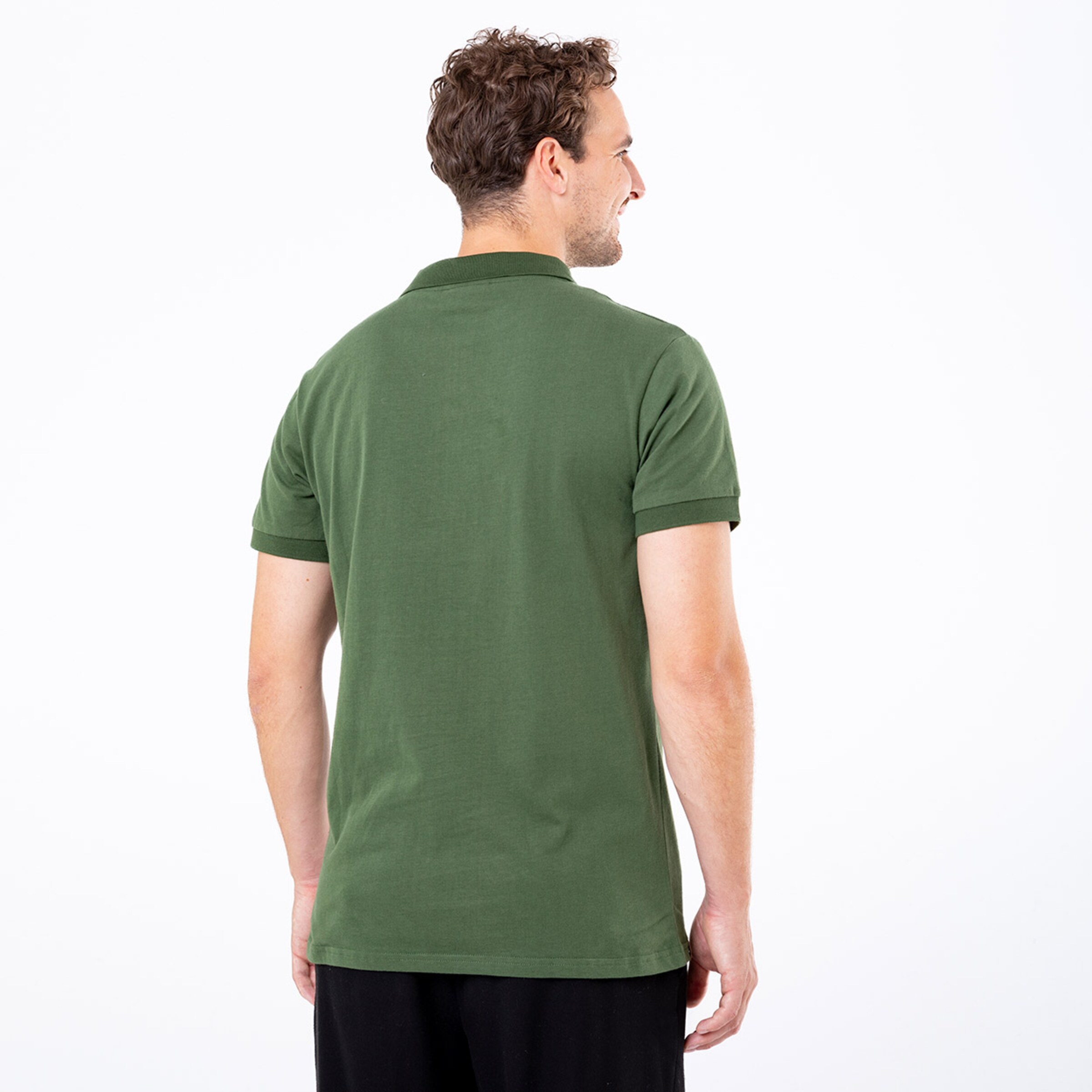 Man wearing a green polo shirt looking over his shoulder.