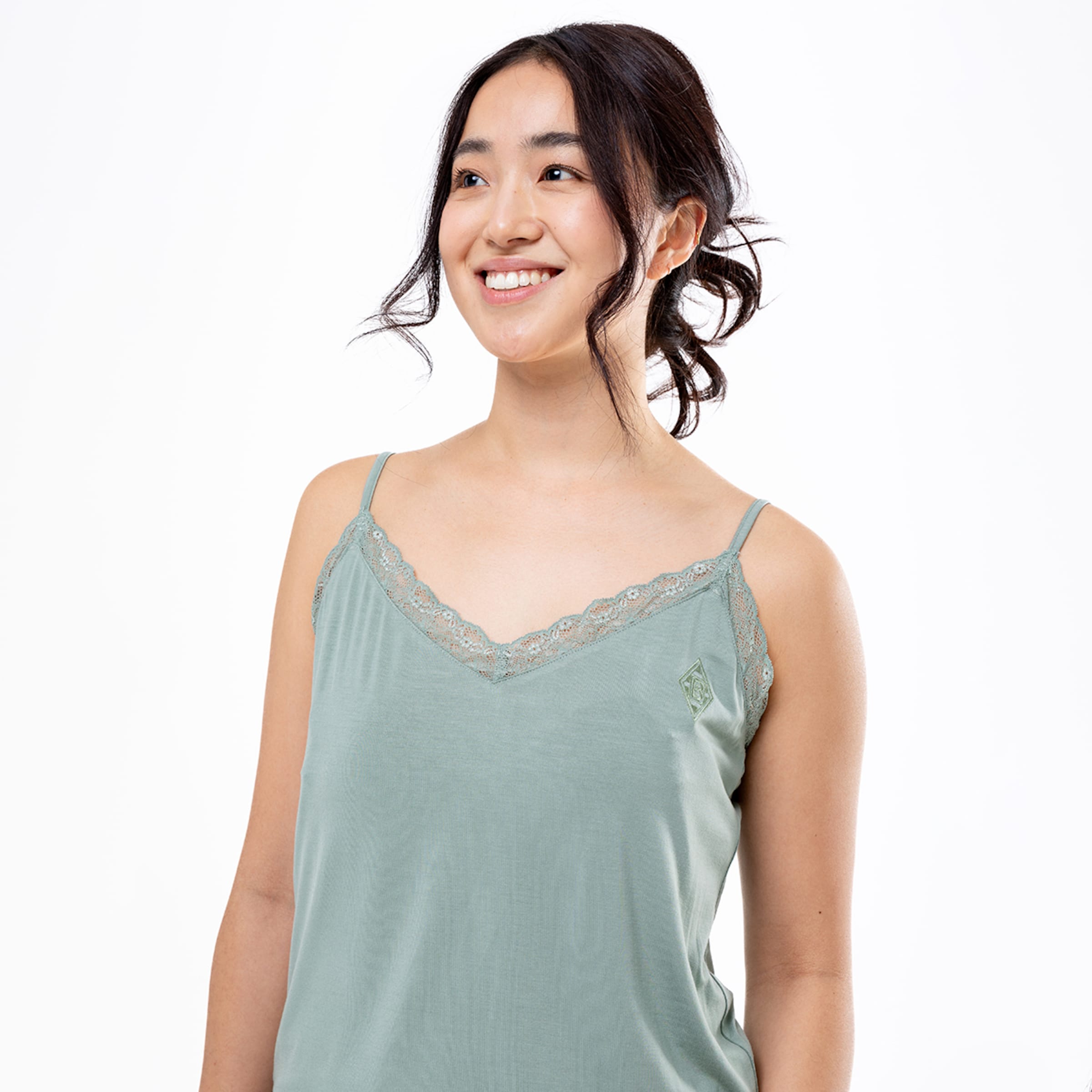 Woman in a green tank top with lace trim and a smiling expression.