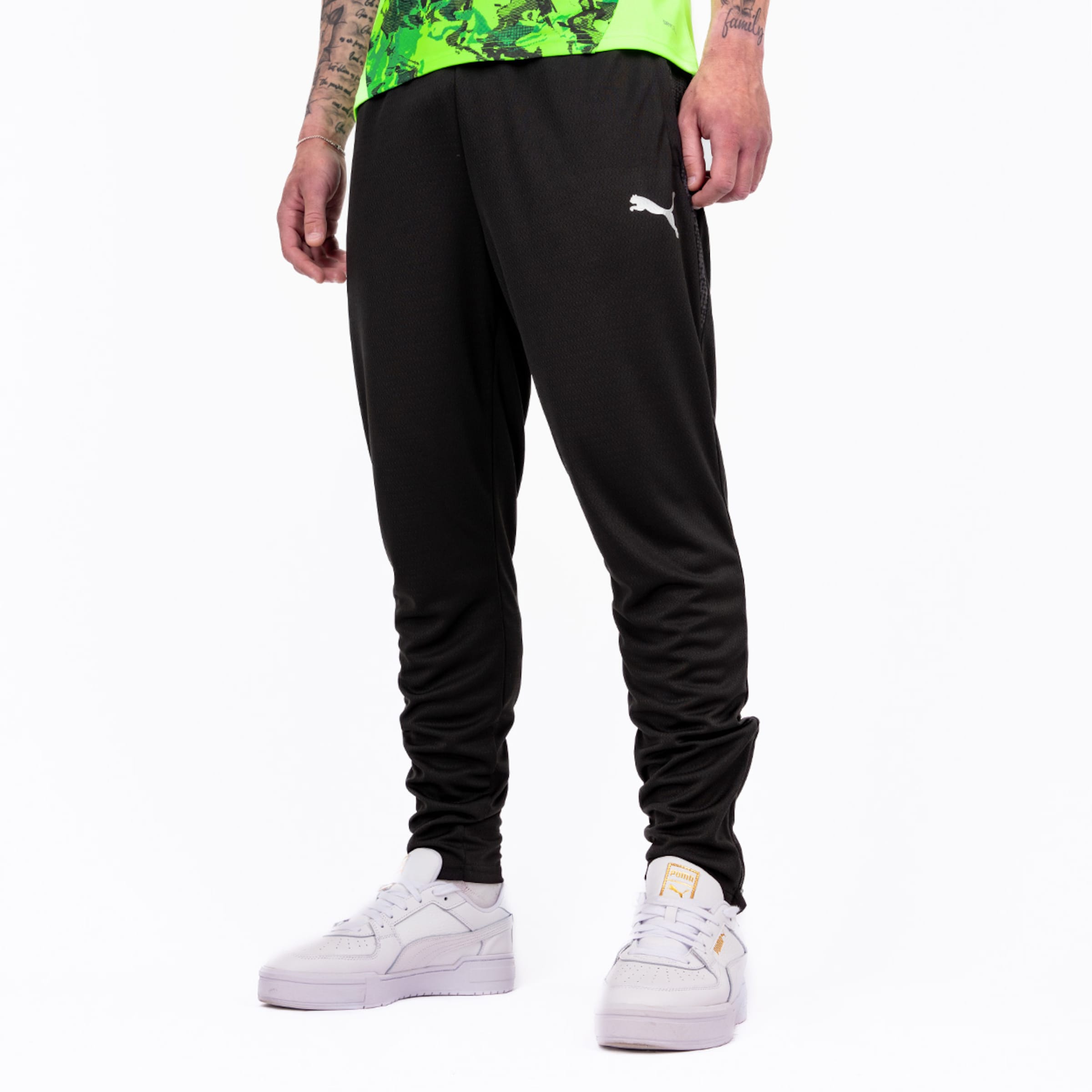 Schwarze Sporthose von Puma enge Passform getragen von einem stehenden Mann in Turnschuhen.