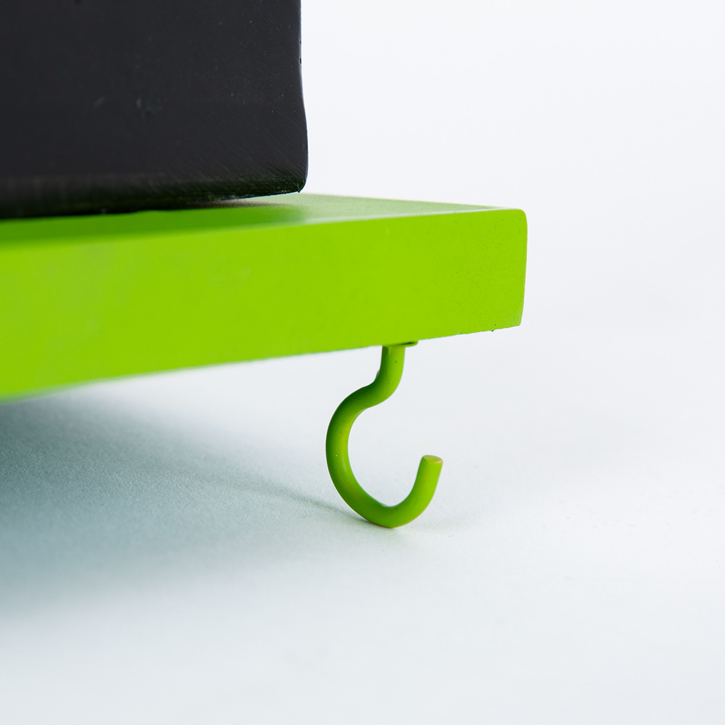 Grüner Haken der an einer Kante eines Objekts befestigt ist.