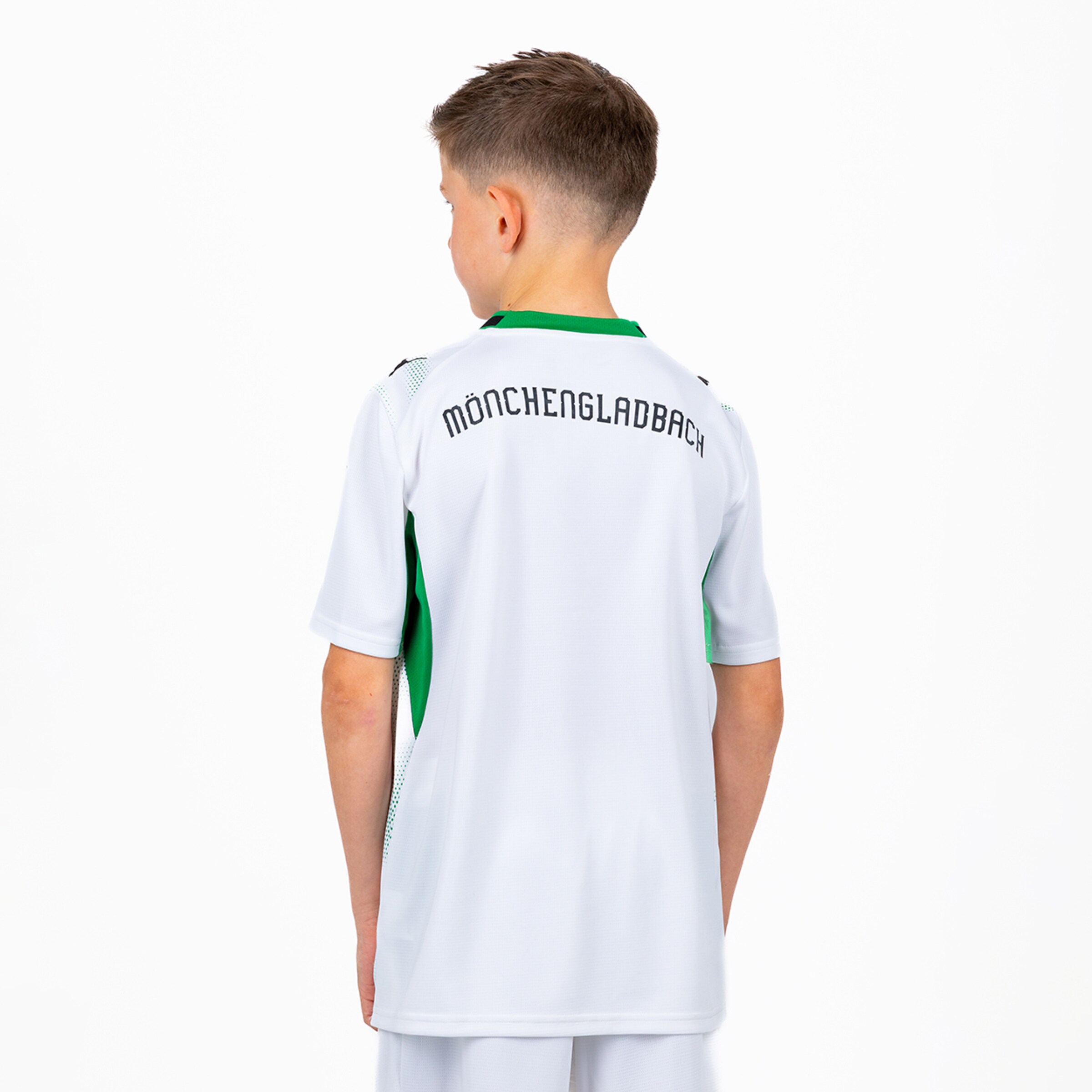 Rückansicht eines Jungen im weißen Fußballtrikot mit grünem Kragen und dem Schriftzug „MÖNCHENGLADBACH“ auf dem Rücken.