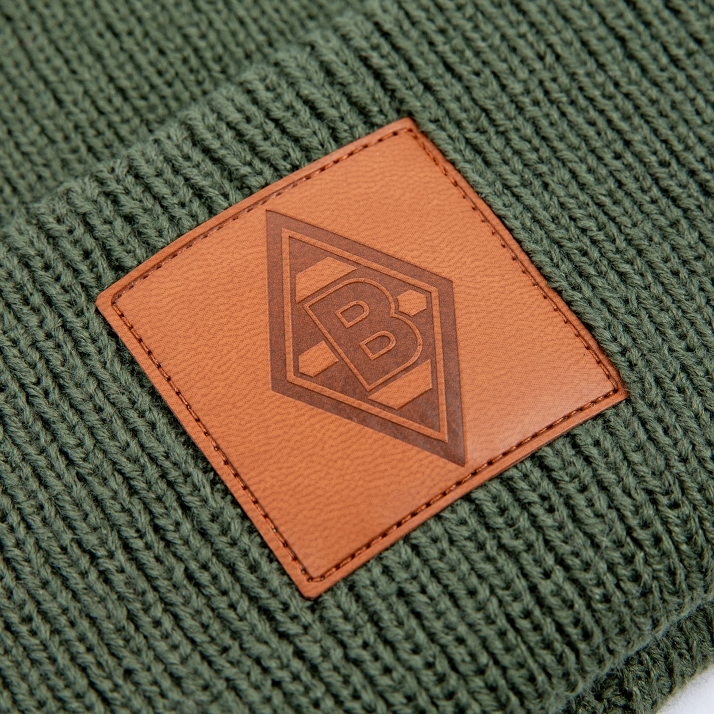 Braunleder-Patch mit Borussia Mönchengladbach-Logo auf einer grünen Strickmütze.