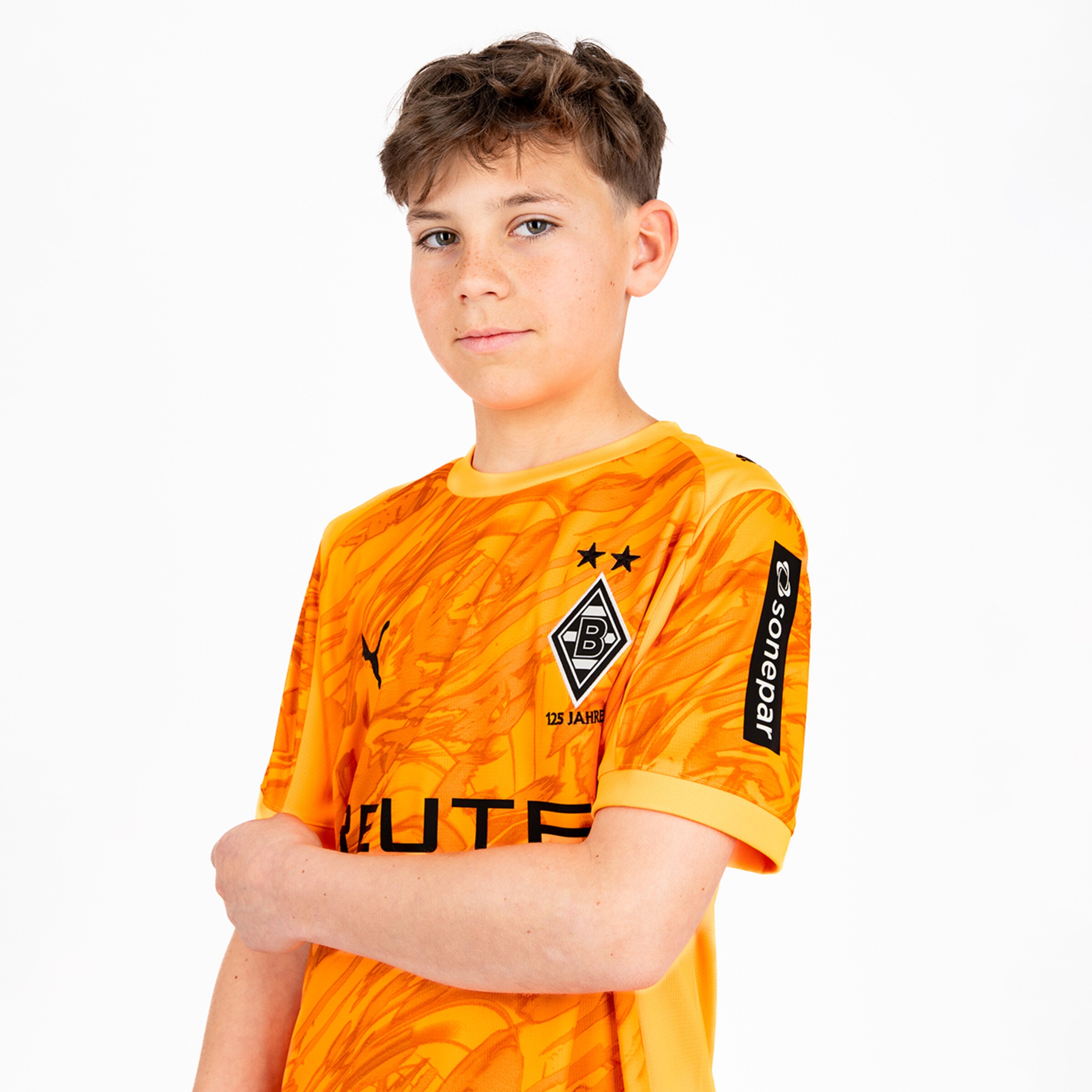 Junge trägt ein oranges Borussia Mönchengladbach Trikot mit Logo.