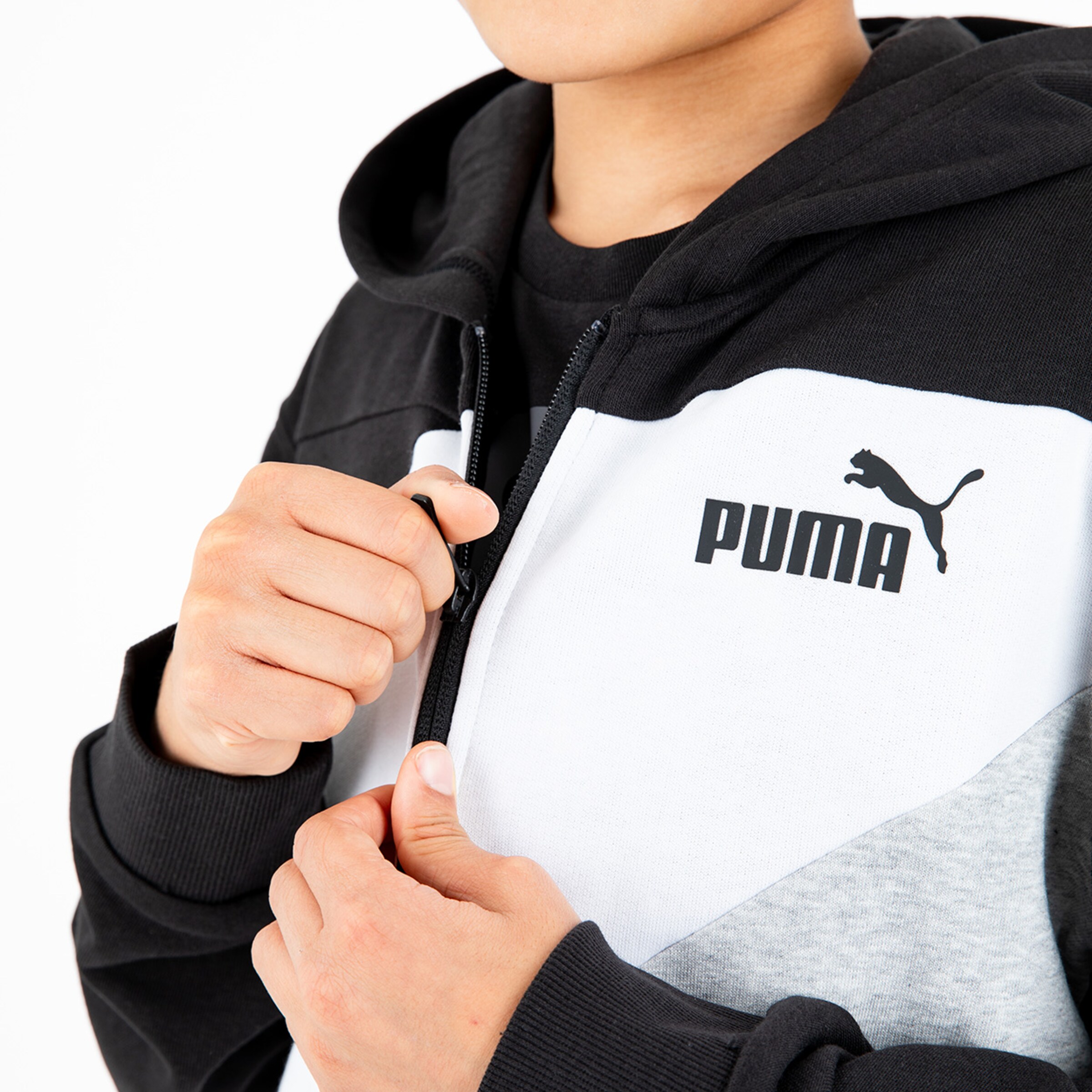 A person zipping up a Puma jacket.