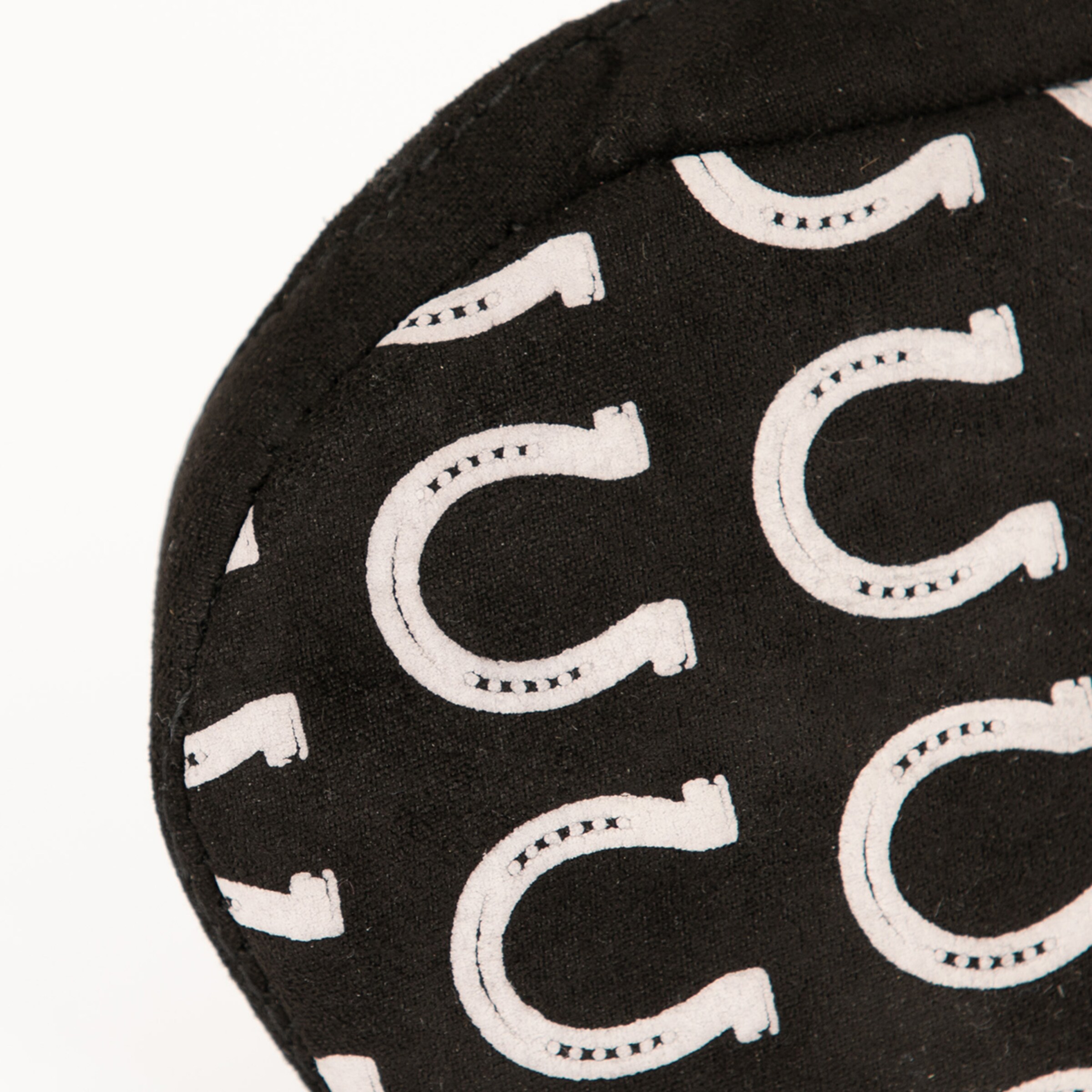 Schwarz mit weißen Hufeisen-Muster auf einer runden Textiloberfläche.