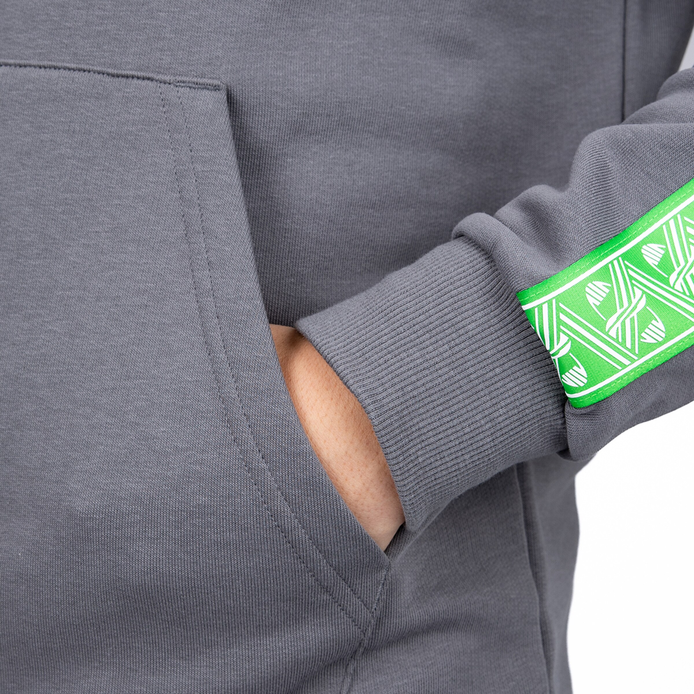 Close-up of a gray hoodie with a hand in the pocket and a vibrant green patterned band on the sleeve.
