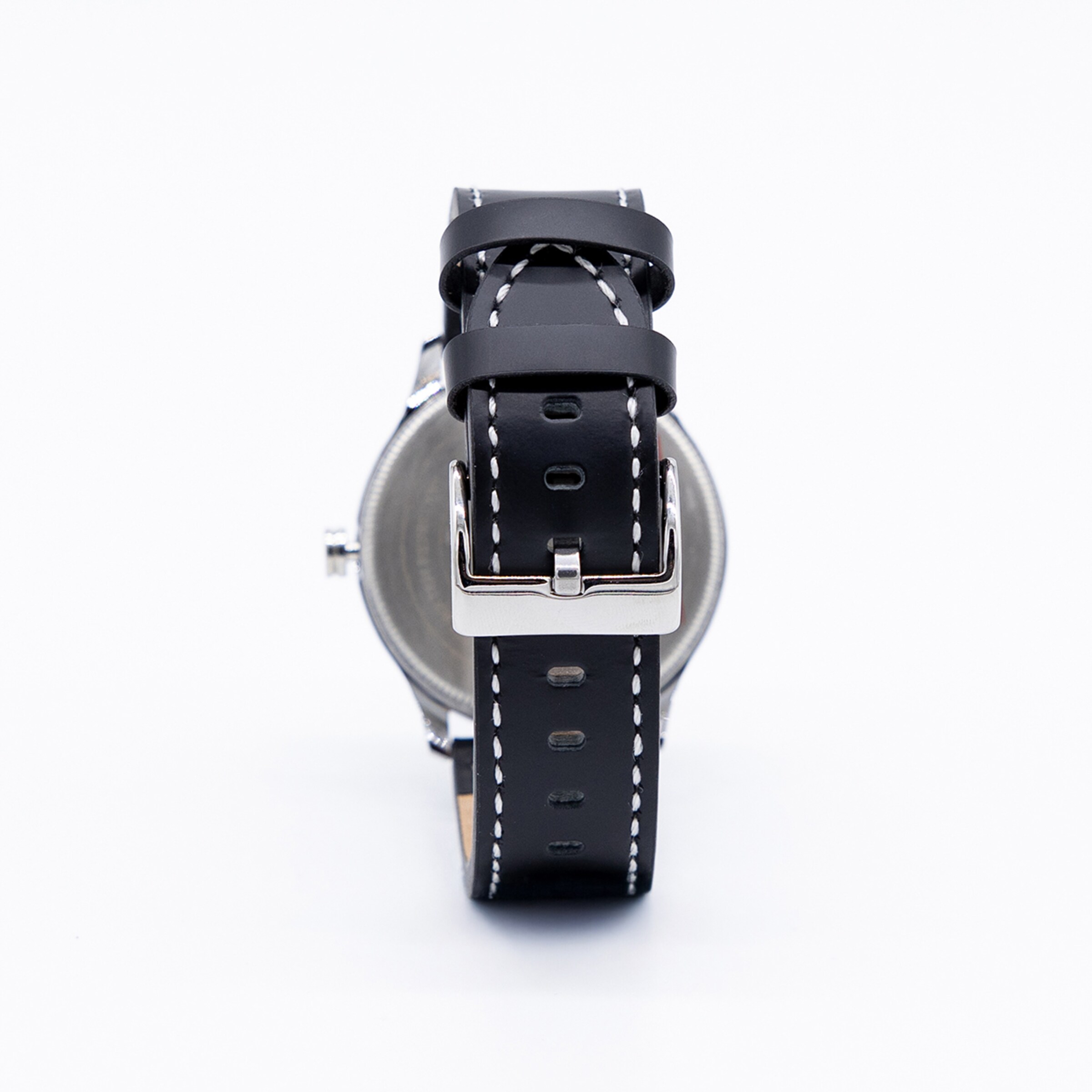 Rückansicht einer Armbanduhr mit schwarzem Lederband, weißer Kontrastnaht und silberner Dornschließe auf weißem Hintergrund.