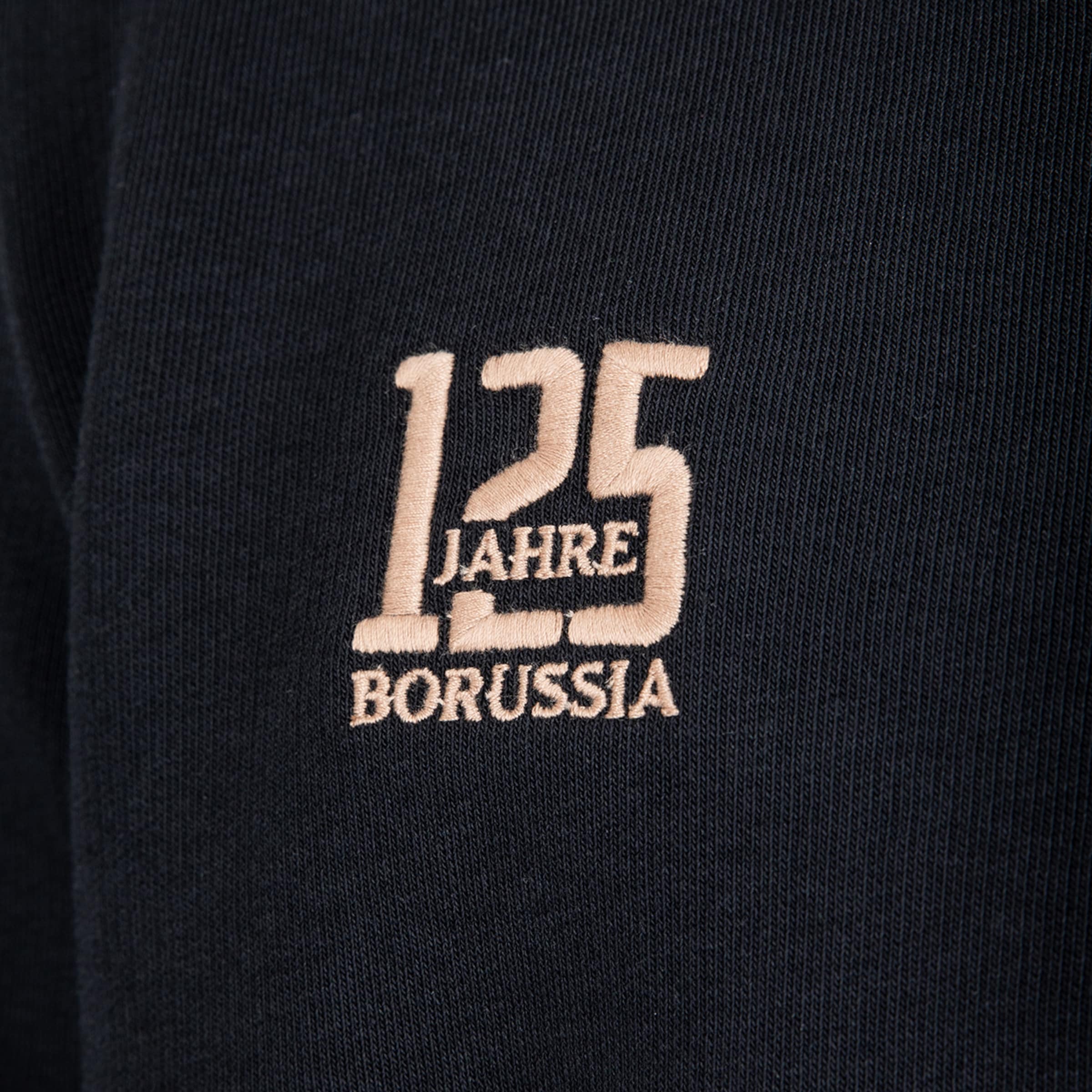 Beige Bestickung auf schwarzem Stoff: Die Zahl „125“ mit integriertem Wort „JAHRE“ und dem Schriftzug „BORUSSIA“ darunter.