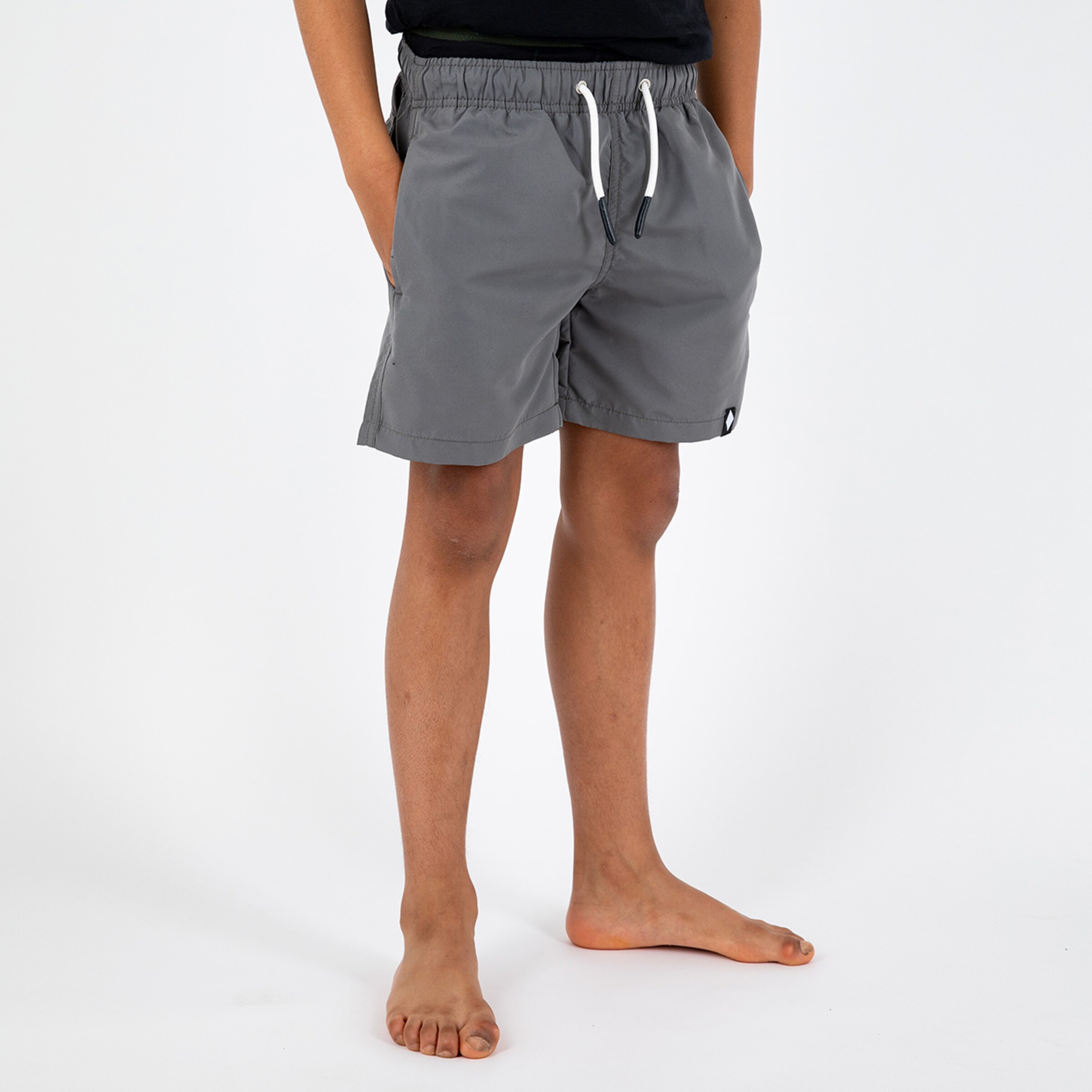 Junge mit grauen Badeshorts und barfuß stehend.