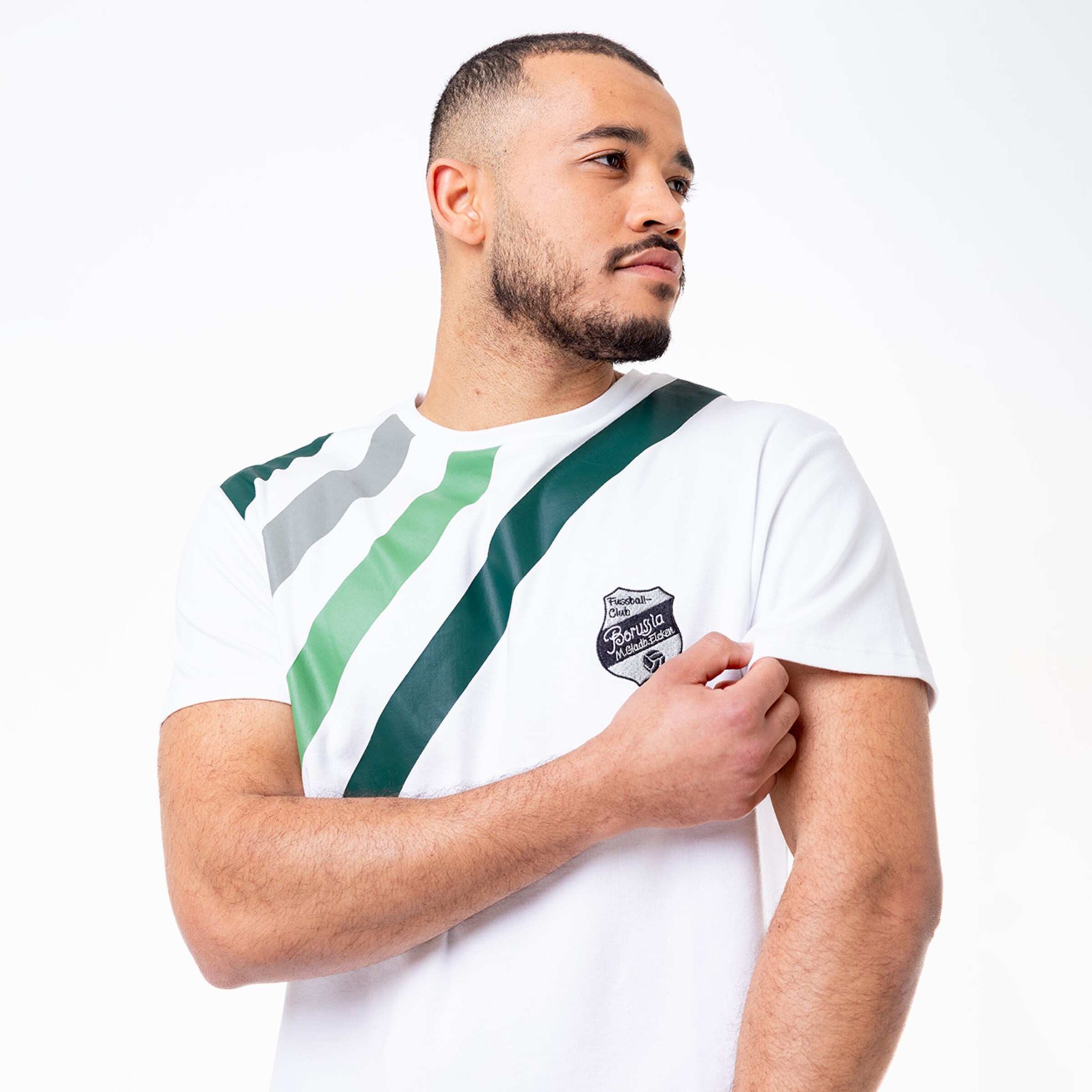 Mann in einem weißen T-Shirt mit grünem und grauem Design zeigt das Logo von Borussia Mönchengladbach.