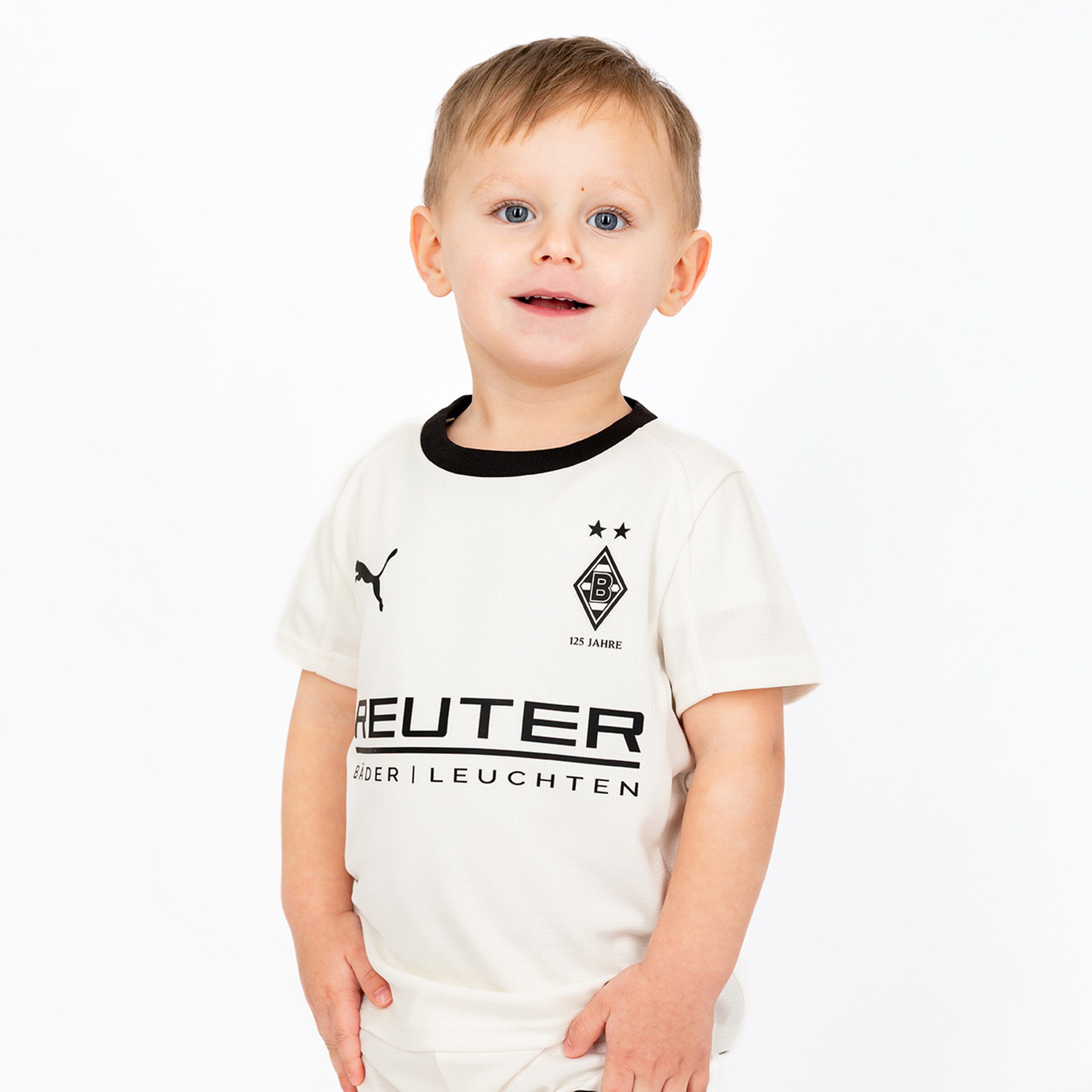 Ein kleiner Junge trägt ein Fußballtrikot von Borussia Mönchengladbach mit dem Aufdruck 125 Jahre.