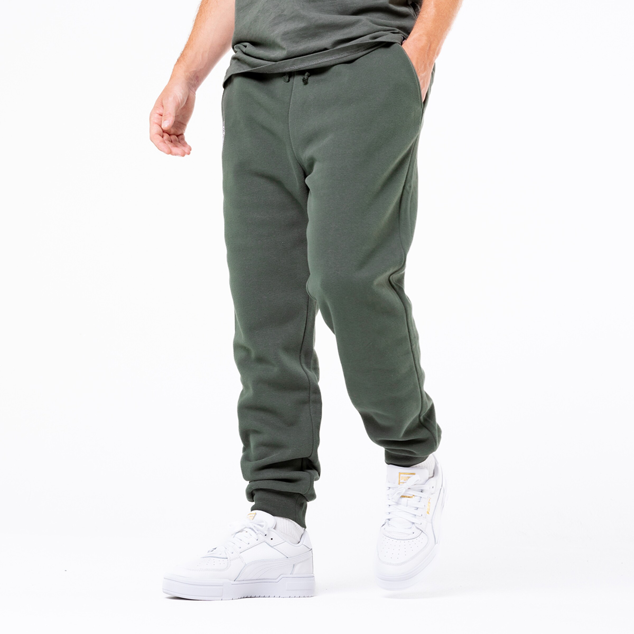 Mann trägt grüne Jogginghose und weiße Sneaker.