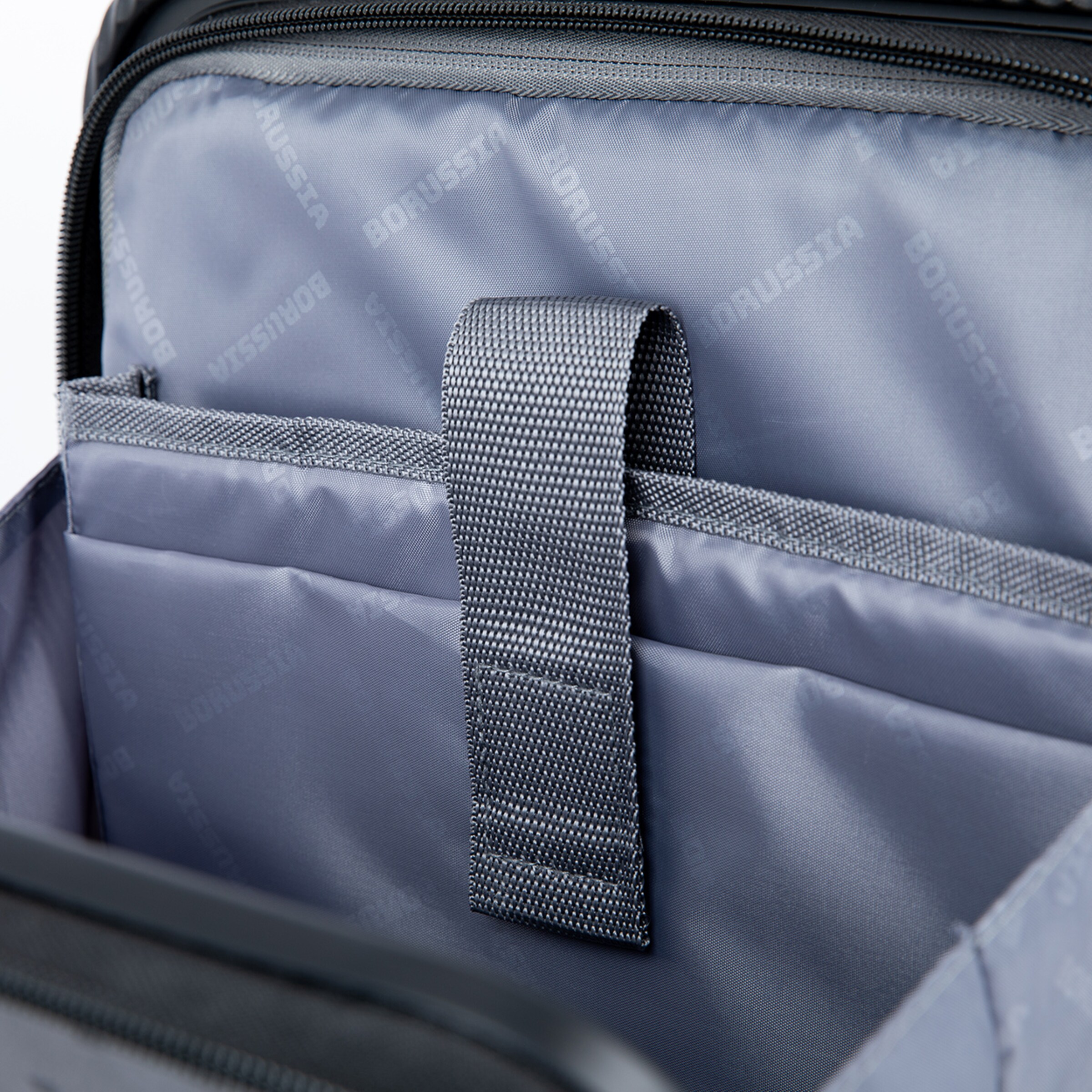 Interior of a bag with gray fabric and a holding strap.