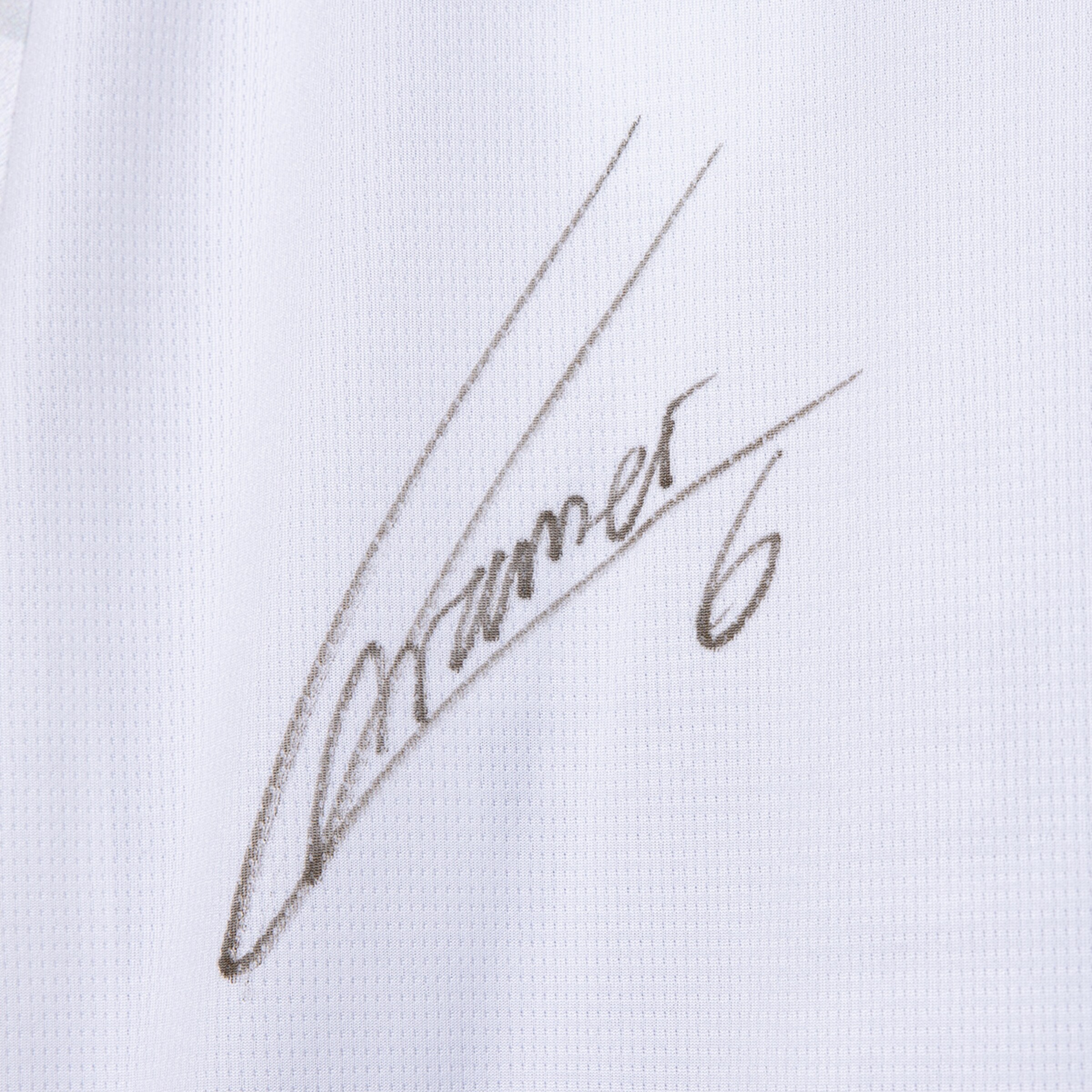 Schwarze handschriftliche Signatur „Kramer“ mit der Nummer 6 auf weißem, strukturiertem Trikotstoff.