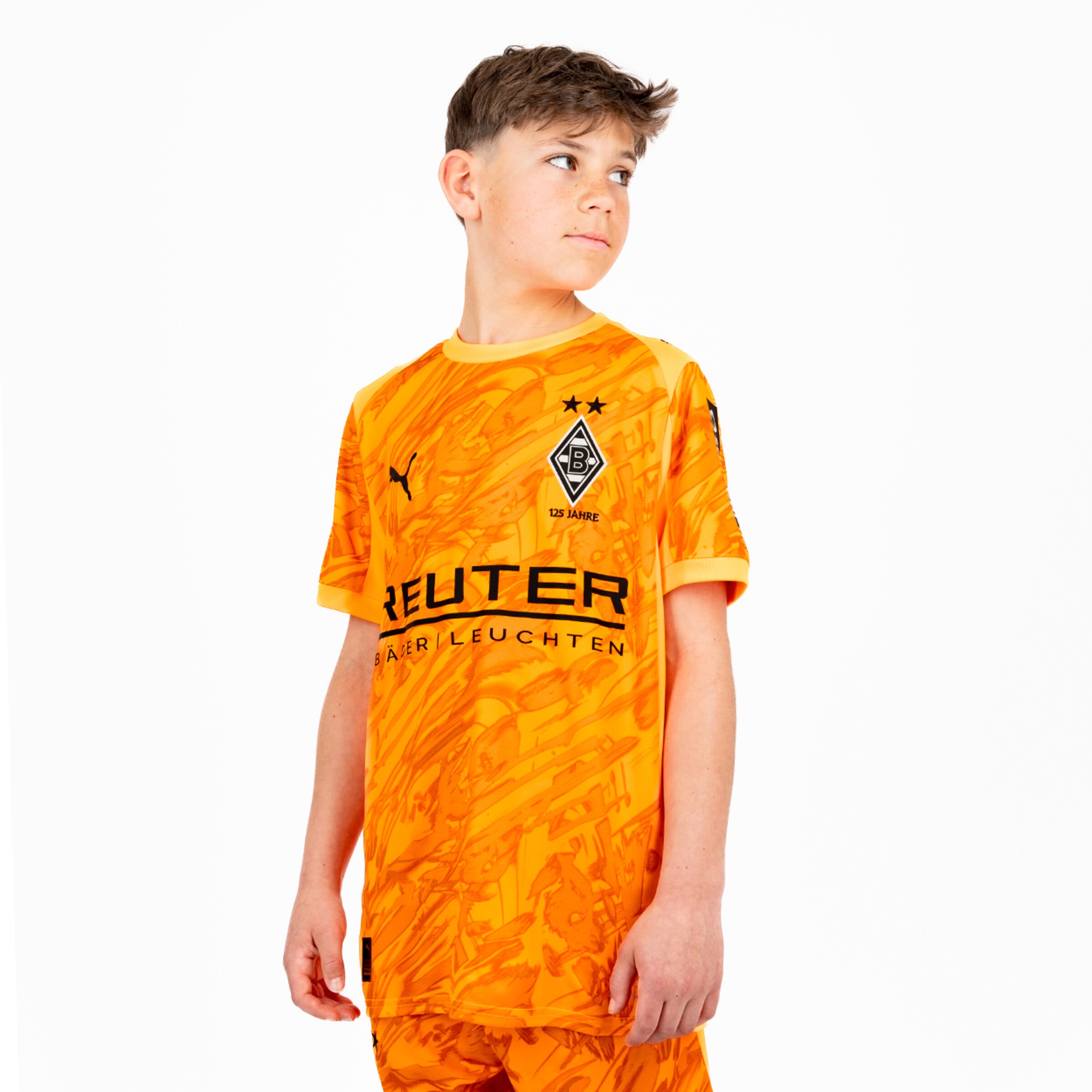 Junge trägt ein orangefarbenes Fußballtrikot von Borussia Mönchengladbach mit dem Namen REUTER.