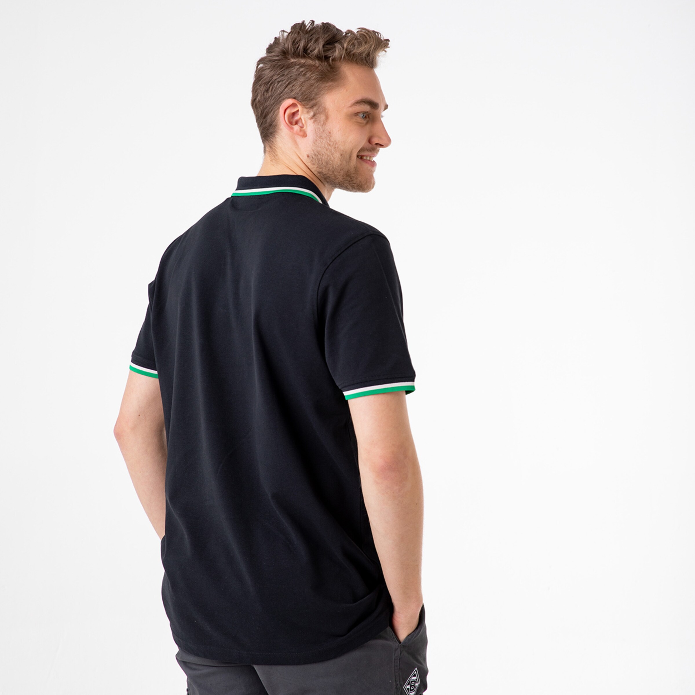 Man wearing a black polo shirt with green and white collar.