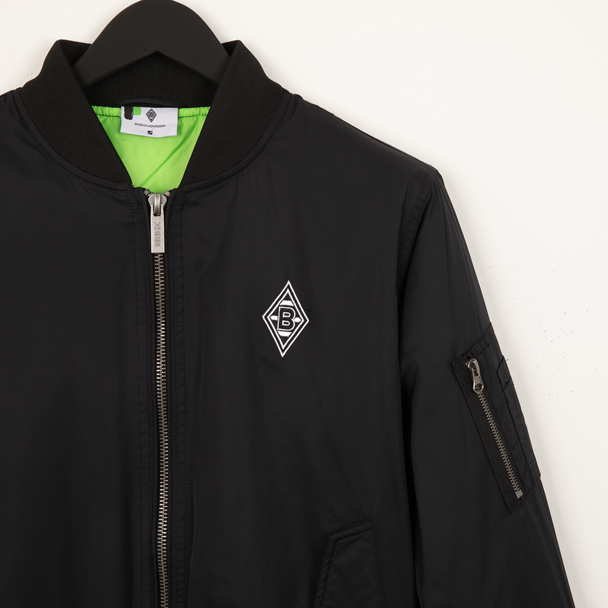 Black bomber jacket with green lining and Borussia Mönchengladbach logo on the chest.
