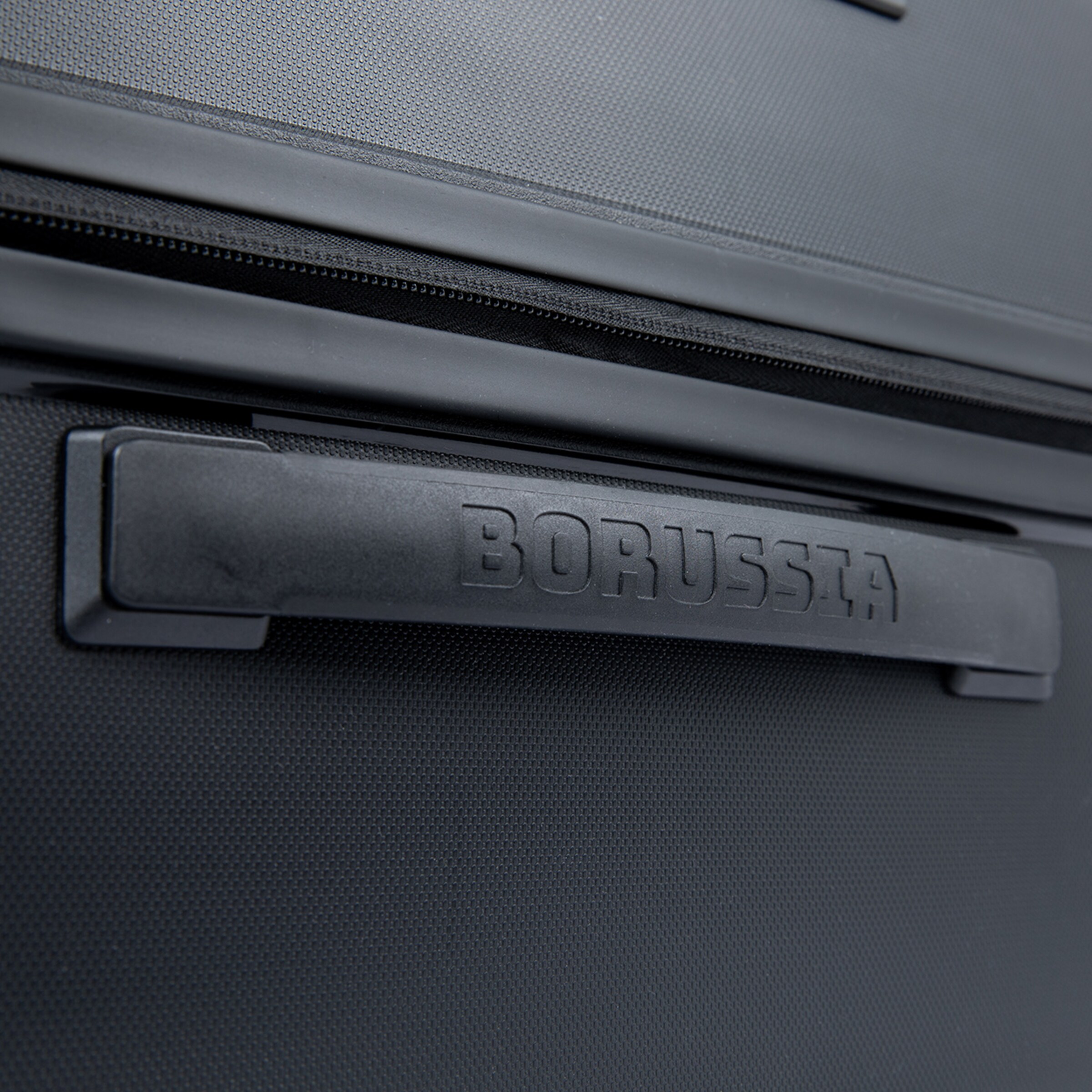 Detailansicht eines Koffers mit einem Griff aus schwarzem Kunststoff und der eingravierten Aufschrift BORUSSIA.