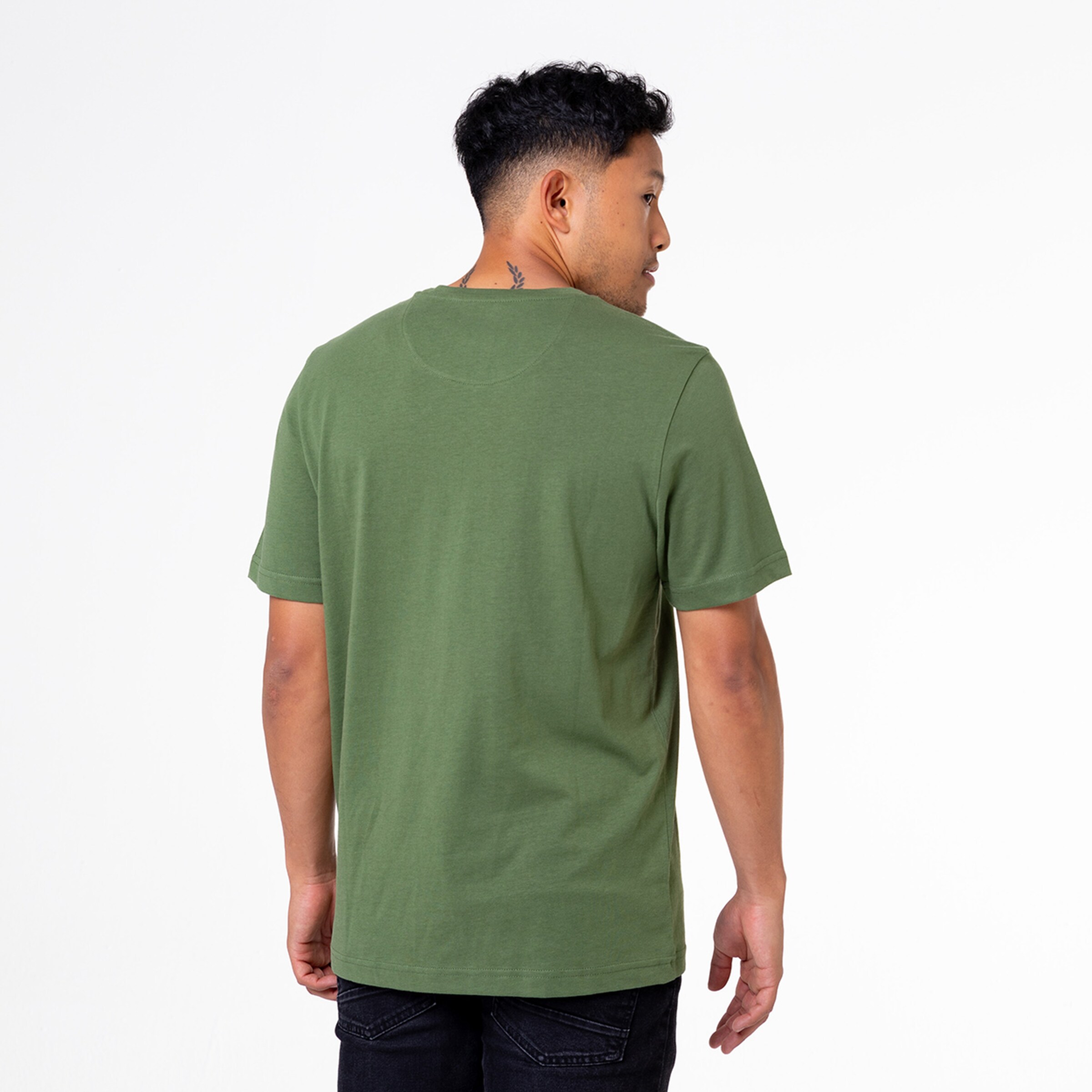 Mann im grünen T-Shirt von hinten mit kurzem schwarzem Hosen zeigt lässige Haltung.