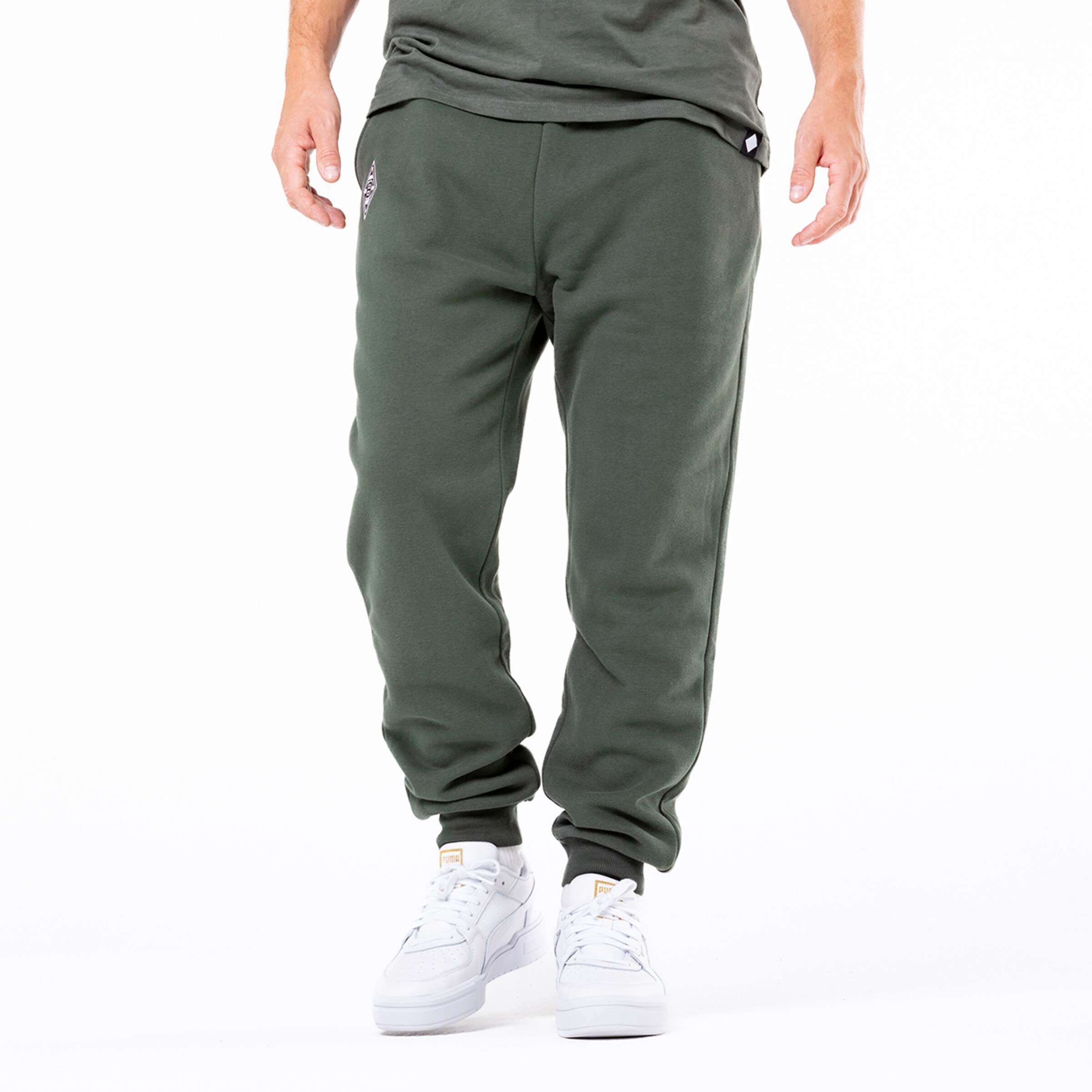 Herren-Sweatpants in Olivgrün mit elastischem Bund und weißen Sneakers.