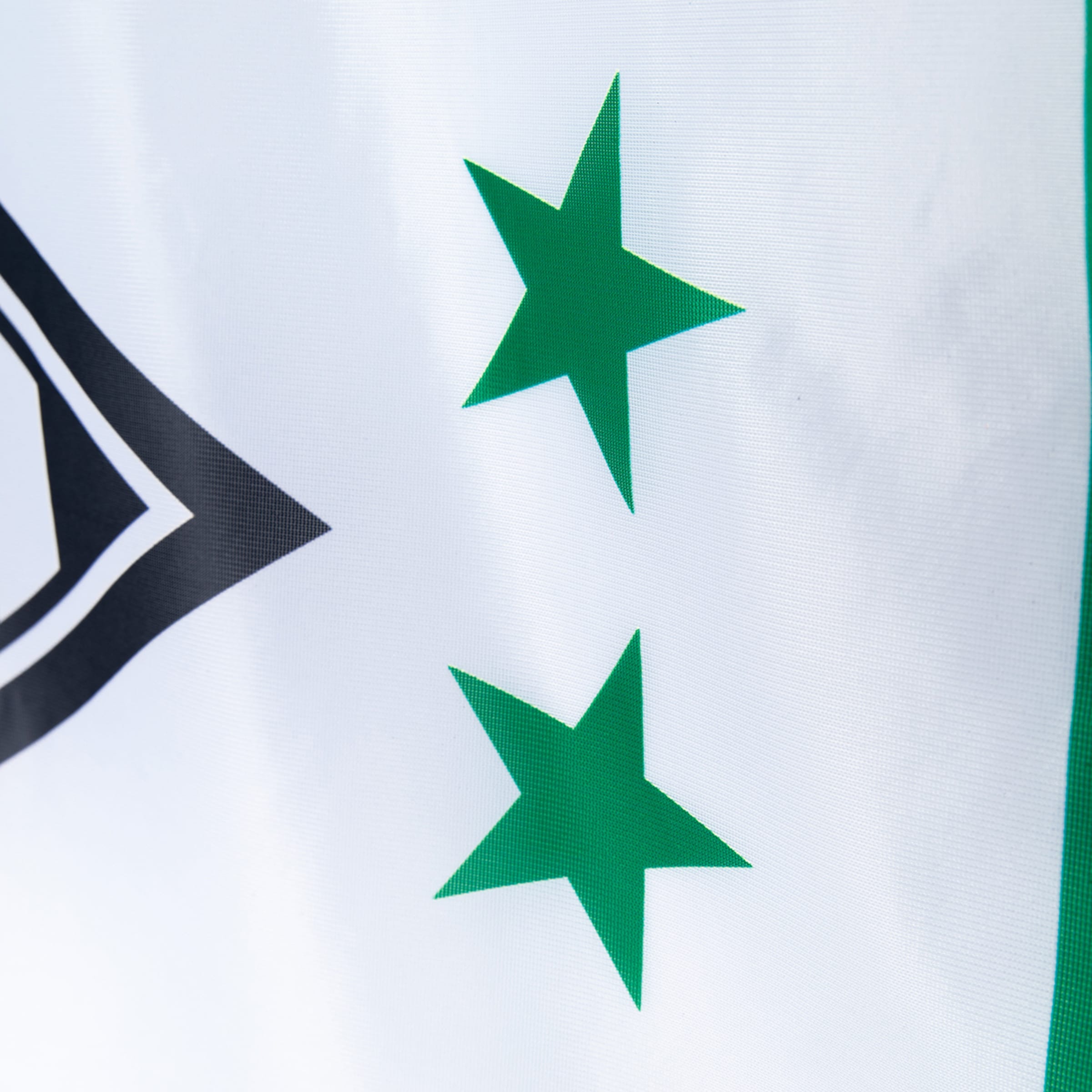Nahaufnahme einer weißen Flagge mit zwei grünen Sternen, einem schwarzen Rauten-Logo links und einem grünen Rand rechts.
