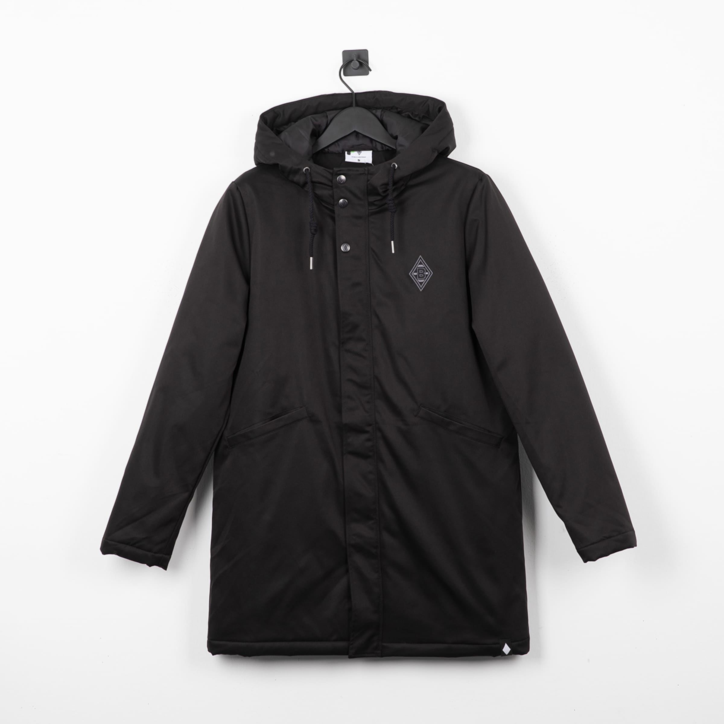Schwarzer Kapuzenparka mit Borussia Mönchengladbach Logo auf der Brust, hängend an einem Kleiderbügel vor einer weißen Wand.