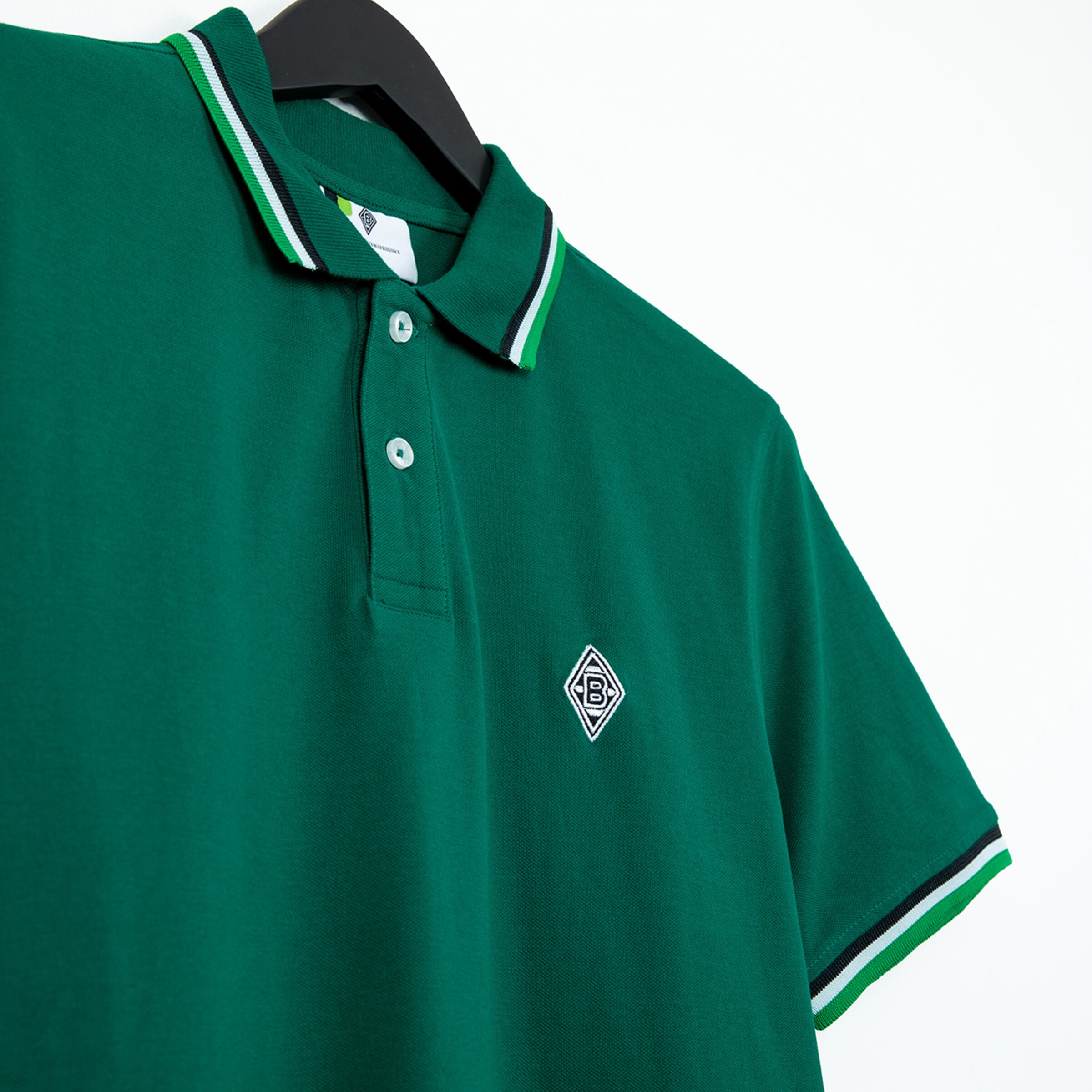 Grünes Polo-Shirt mit Kragen und Vereinslogo von Borussia Mönchengladbach.