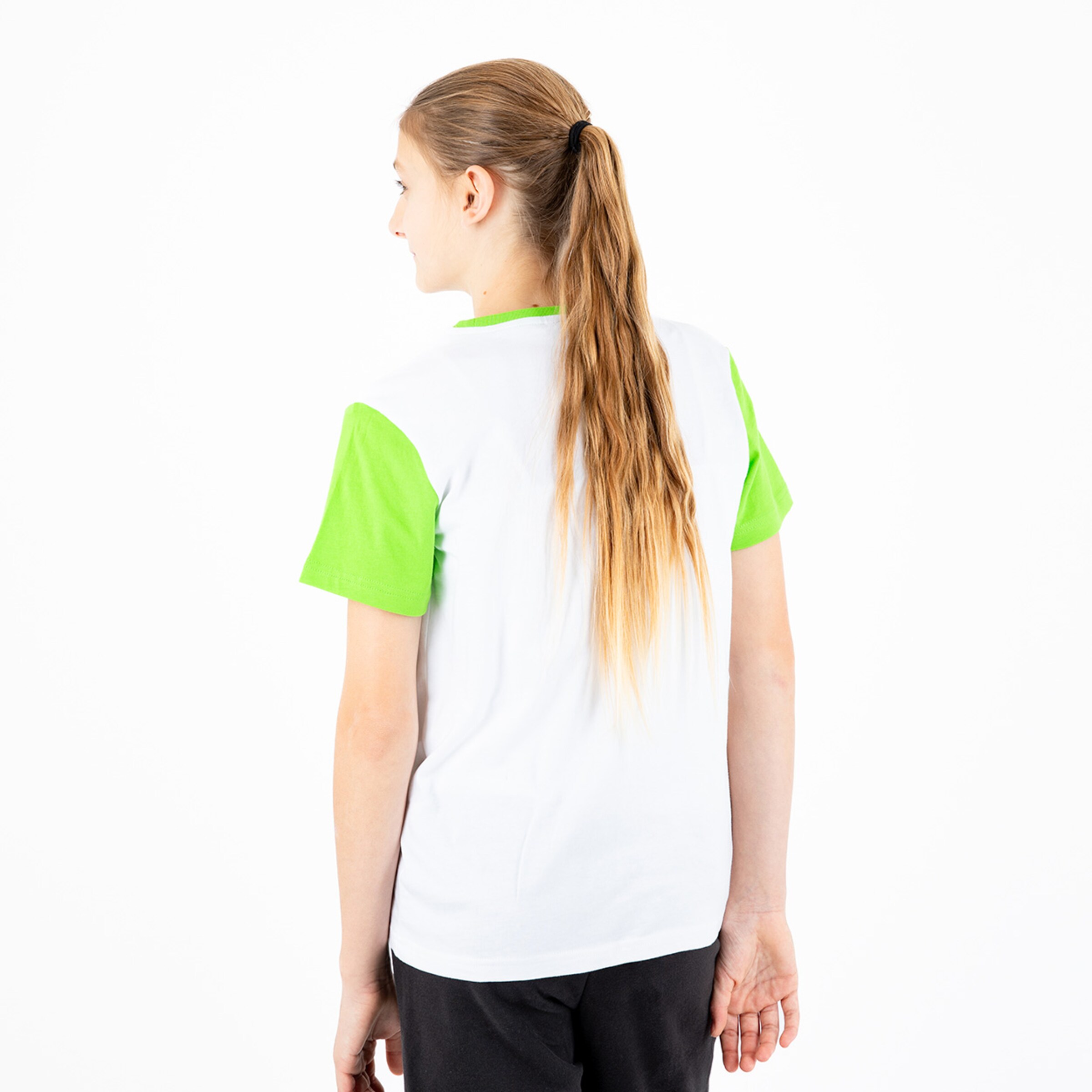 A woman with long blonde hair is wearing a white shirt with green sleeves and is facing away from the camera.