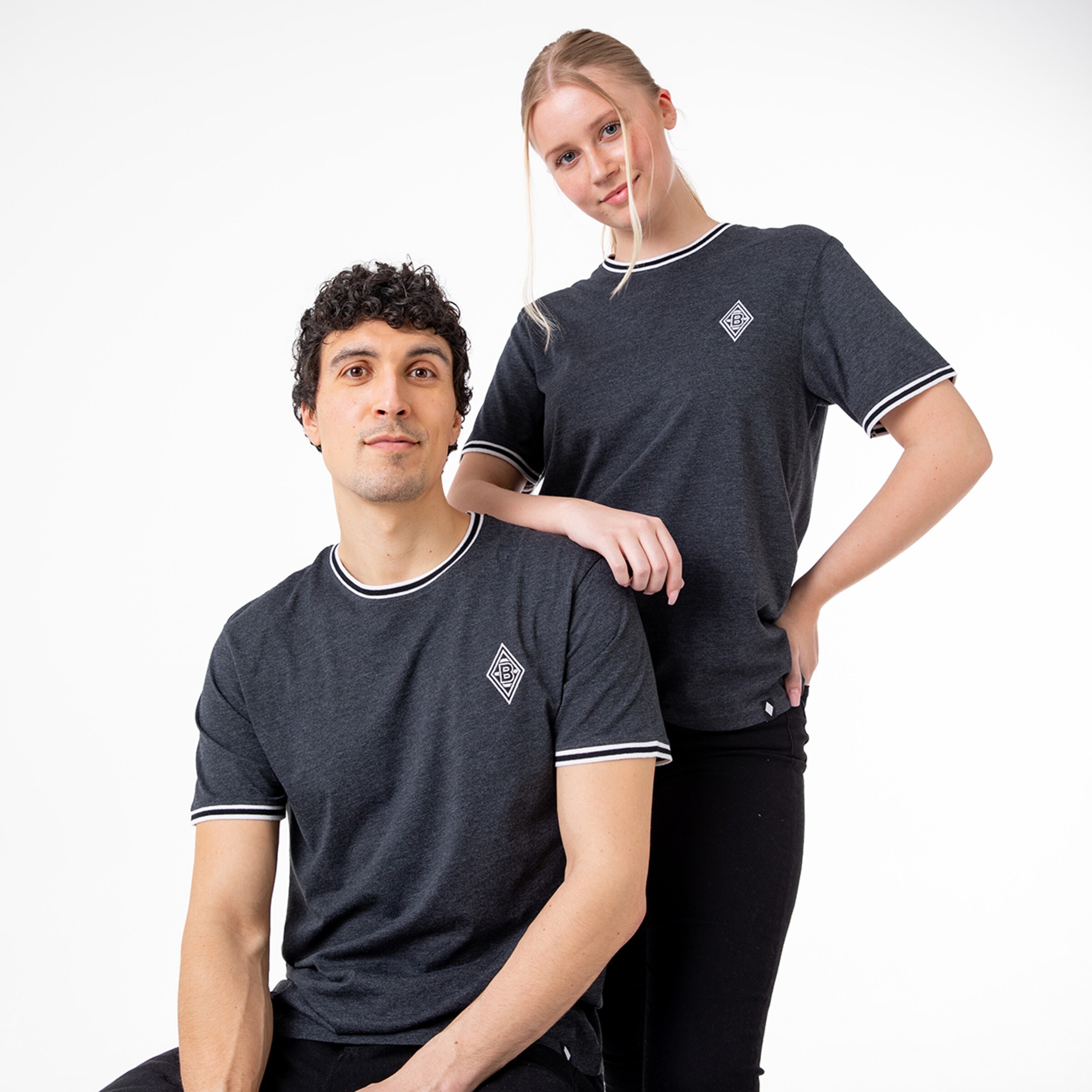Paar trägt graue T-Shirts mit Aufdruck des Vereins Borussia Mönchengladbach.