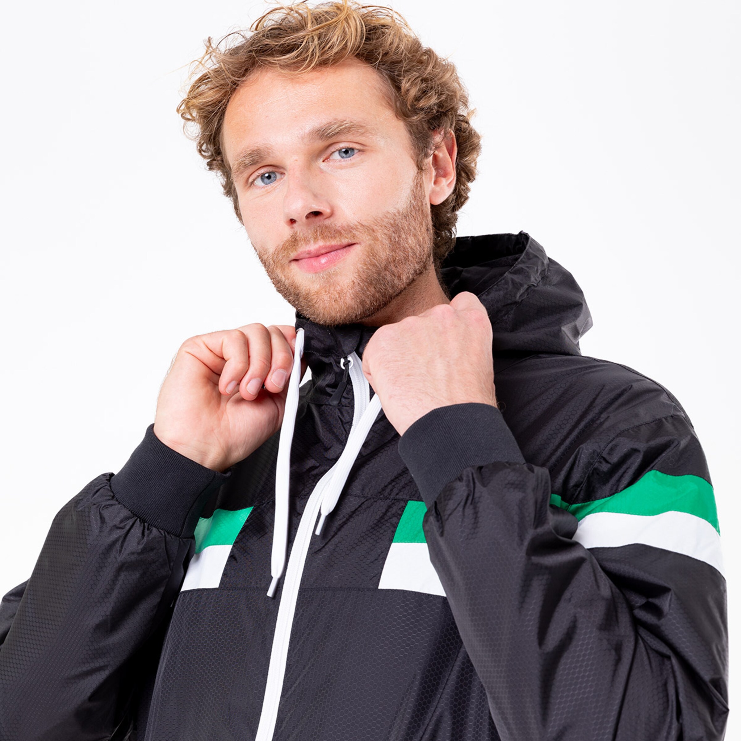 Mann in schwarzer Jacke mit grünem und weißen Streifen der die Kapuze anpasst.